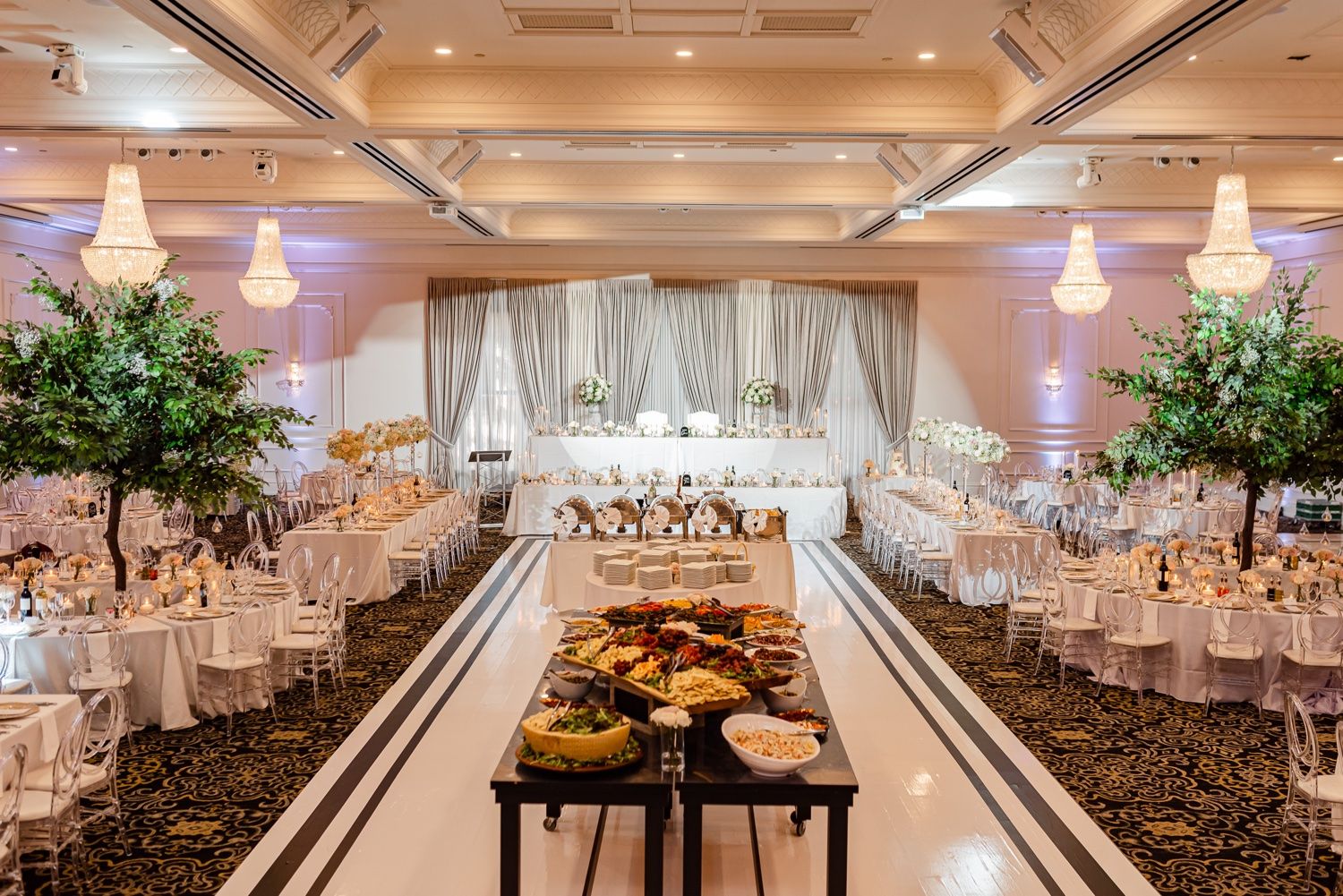Grand ballroom wedding reception setup with dramatic aisle and floral decorations.