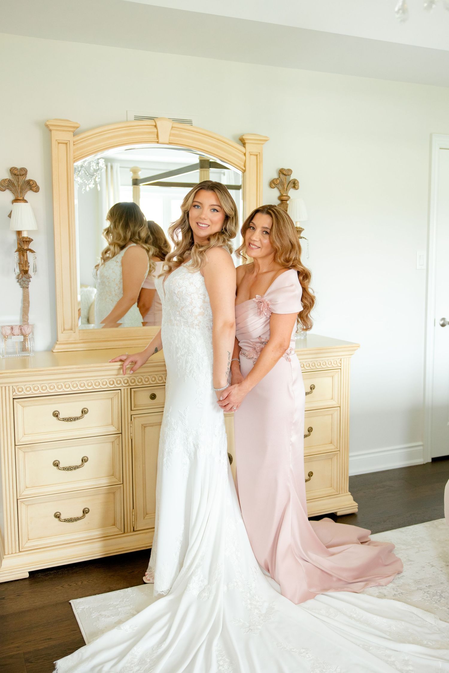 Wedding day preparation with ornate vanity mirror and floor-length gowns.