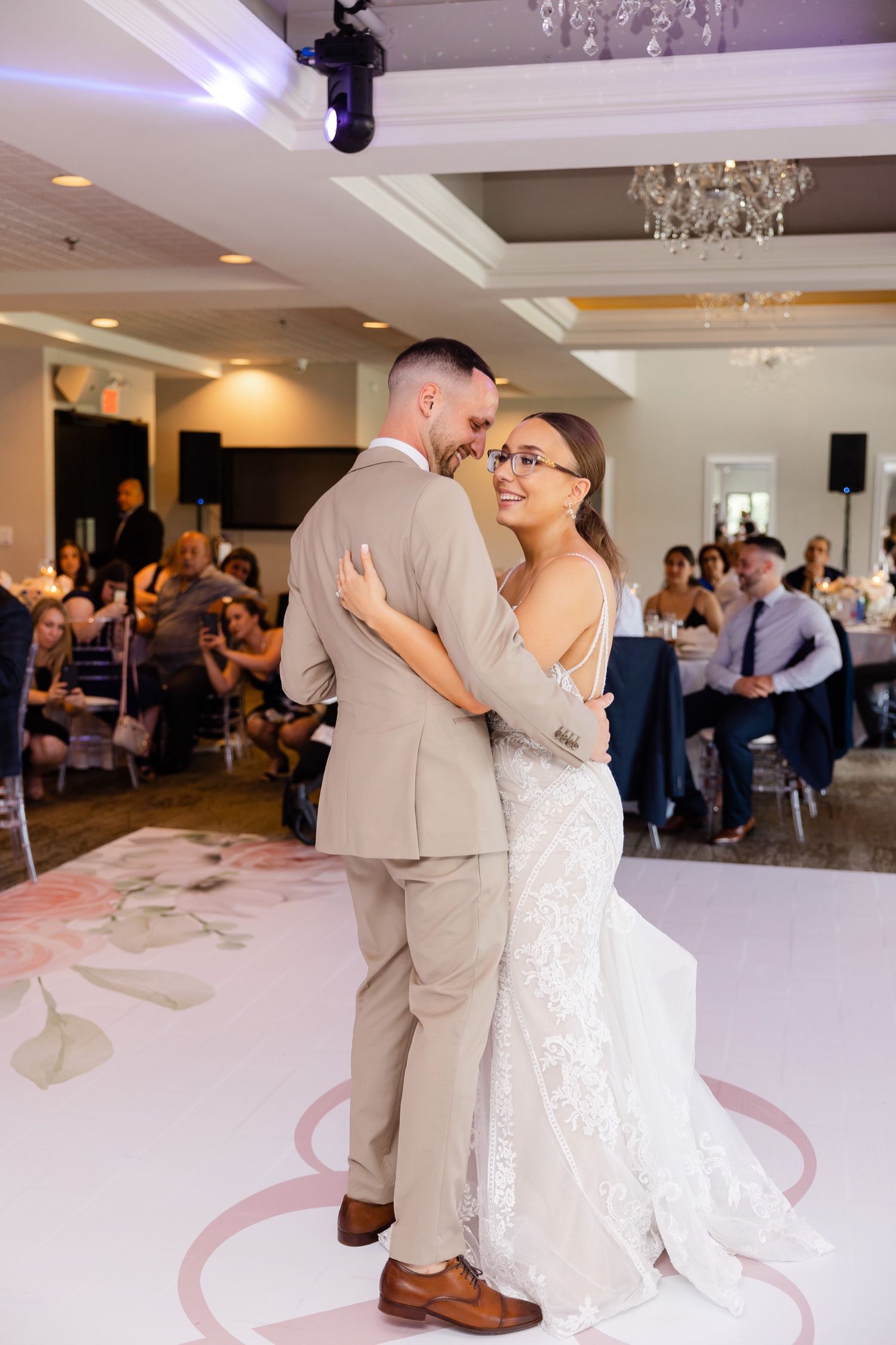 Romantic first dance moment at wedding reception with elegant chandelier lighting.
