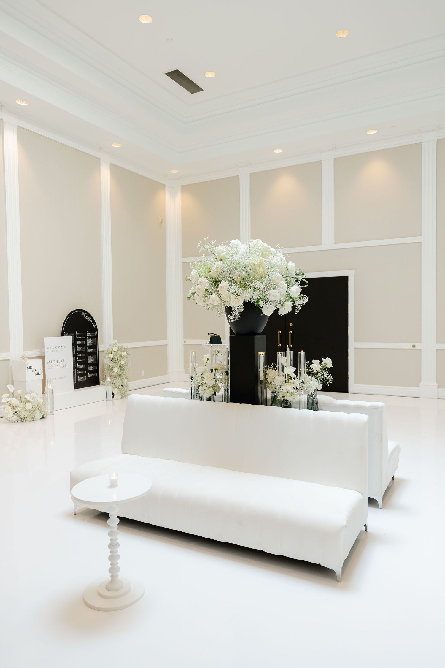 All-white modern wedding reception space with elegant lounge seating and floral arrangements.