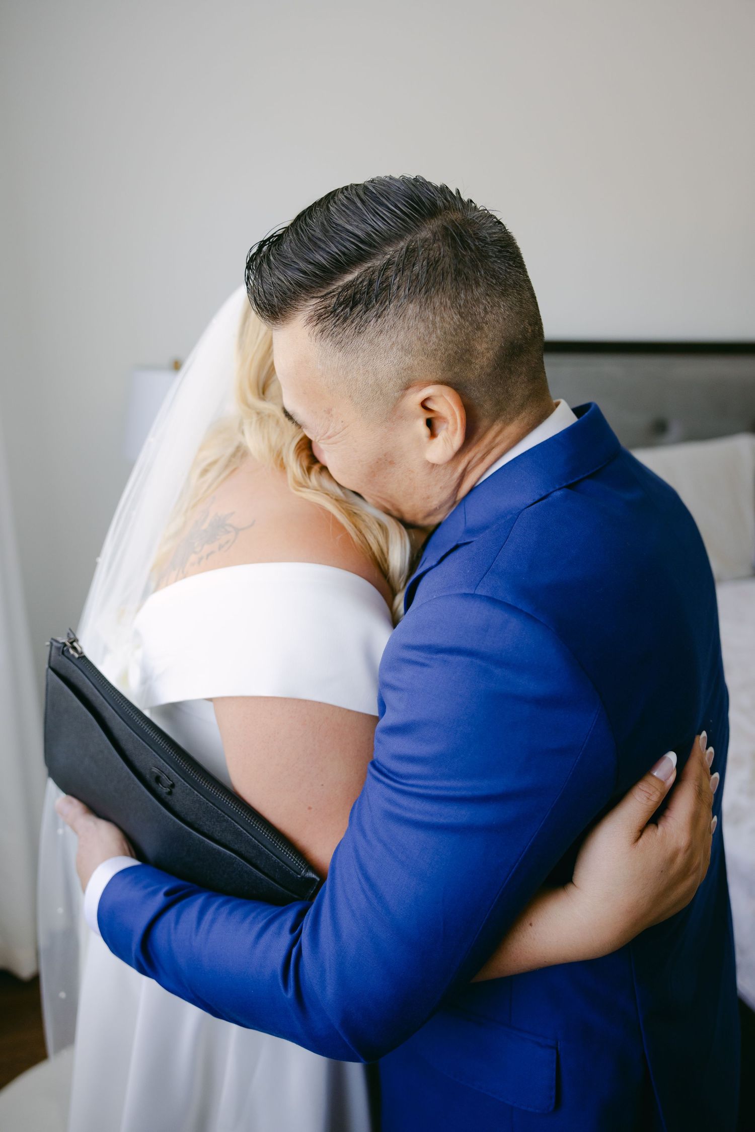 Emotional first look moment between couple at wedding, with groom in blue suit embracing bride.