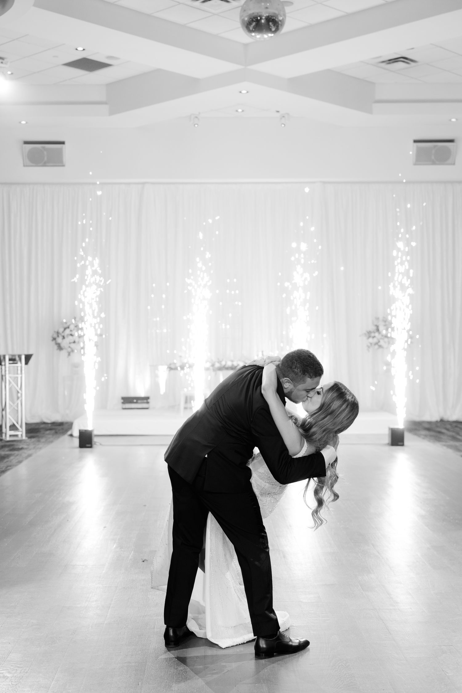 Black and white photo of a romantic dance dip in an elegant wedding reception venue.