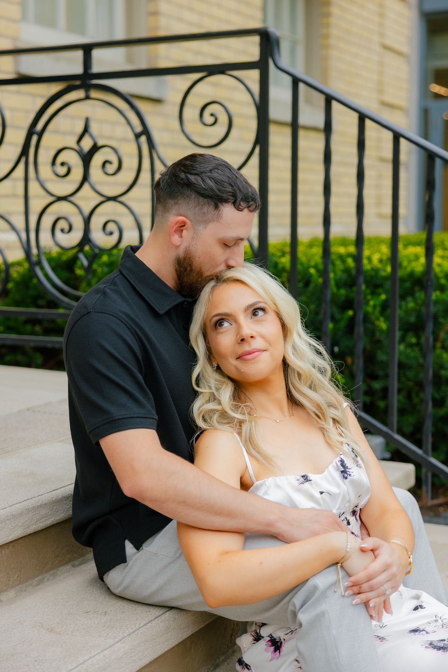A romantic close-up of a couple sharing an intimate moment on steps with wrought iron railings.
