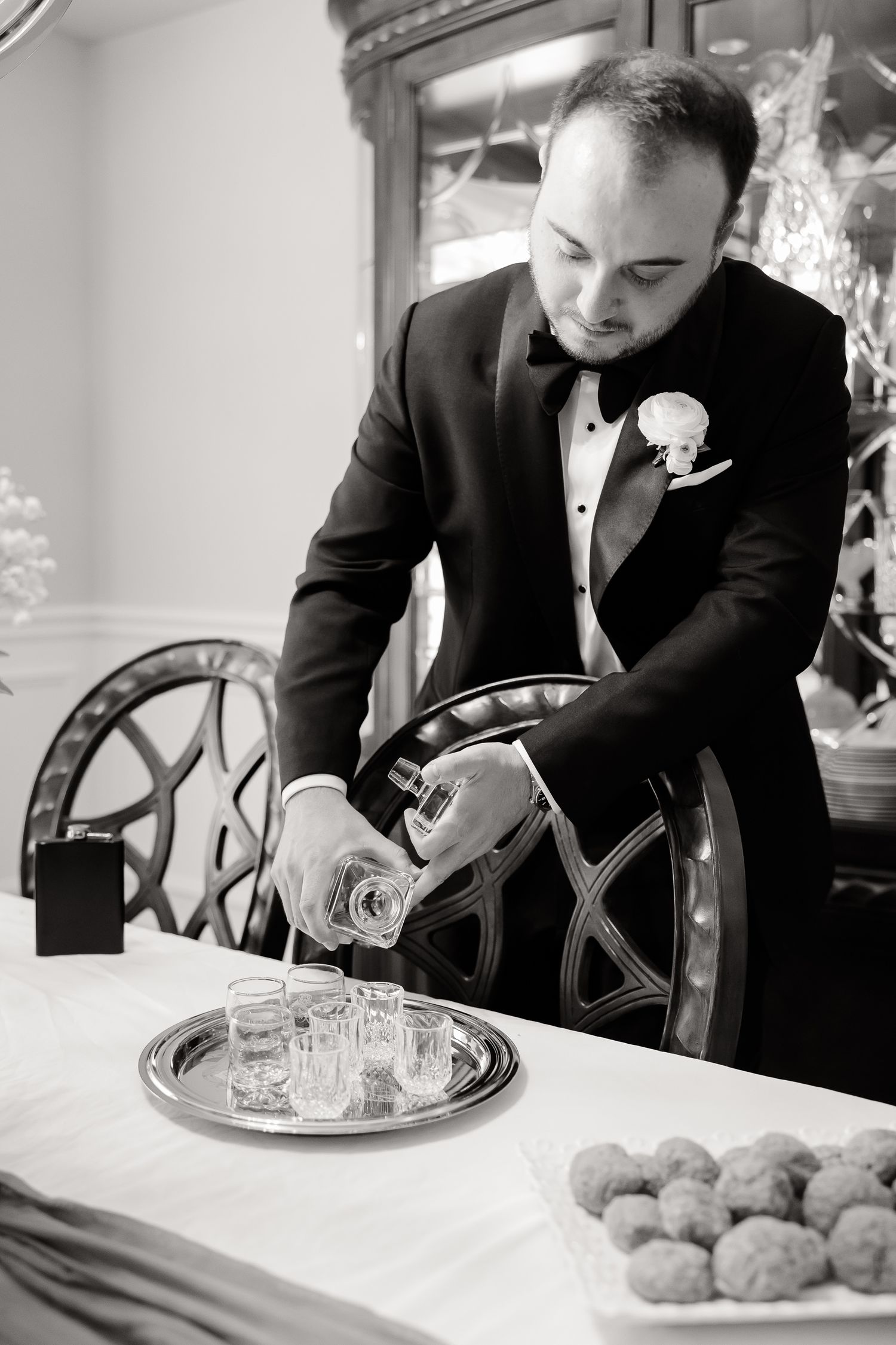 Four black and white photos show someone preparing food and drinks on elegant silver serving trays at an upscale event.