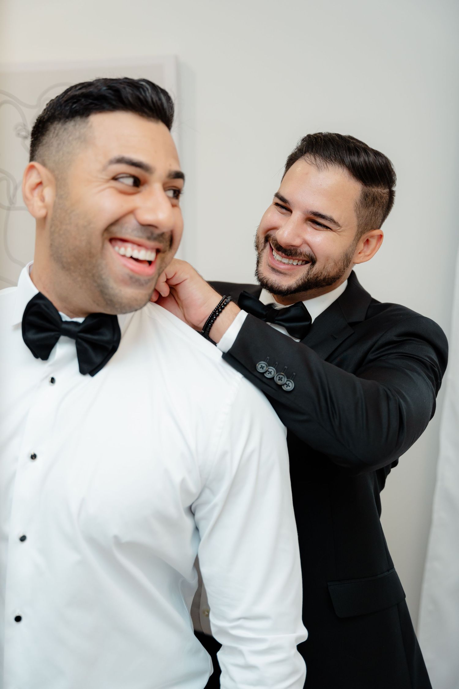Candid moment of groomsmen laughing while getting ready for formal event.
