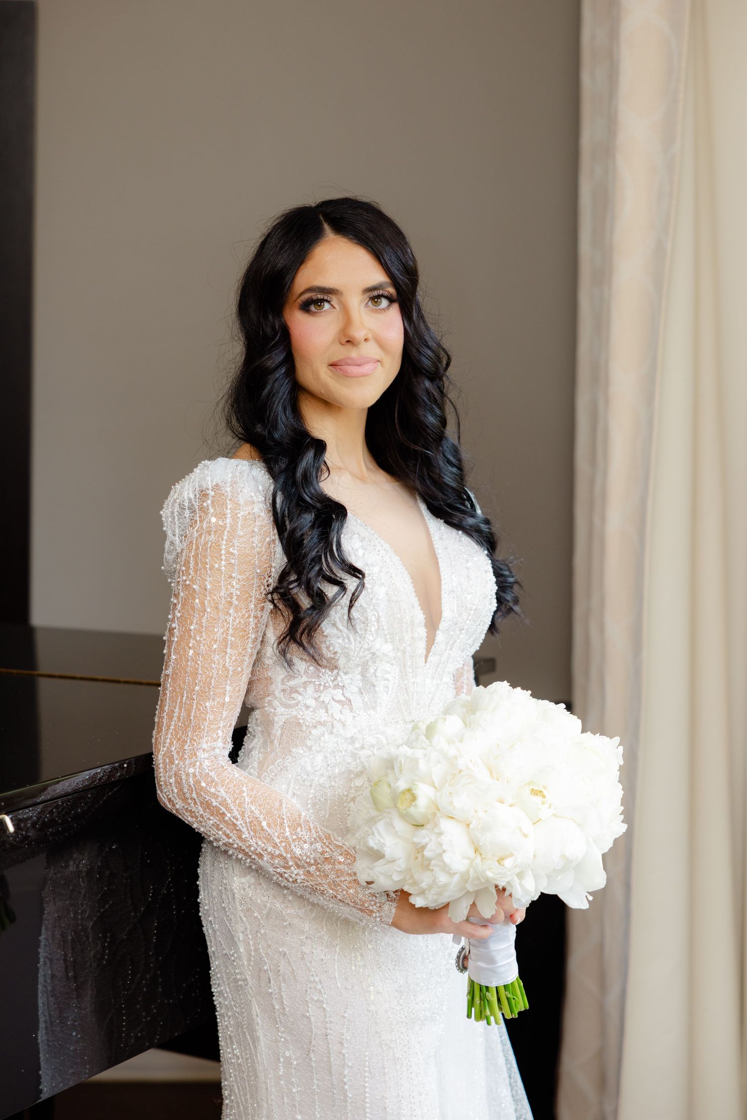 Elegant bridal portrait featuring beaded long sleeve gown and white bouquet.