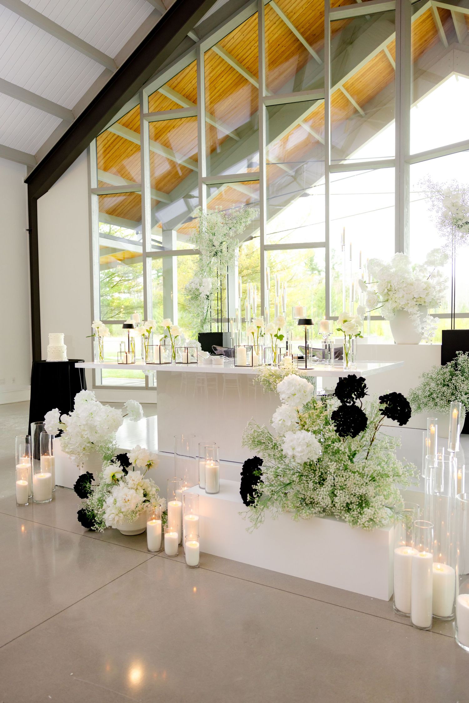 Contemporary wedding venue with black and white floral decor and vaulted ceiling.