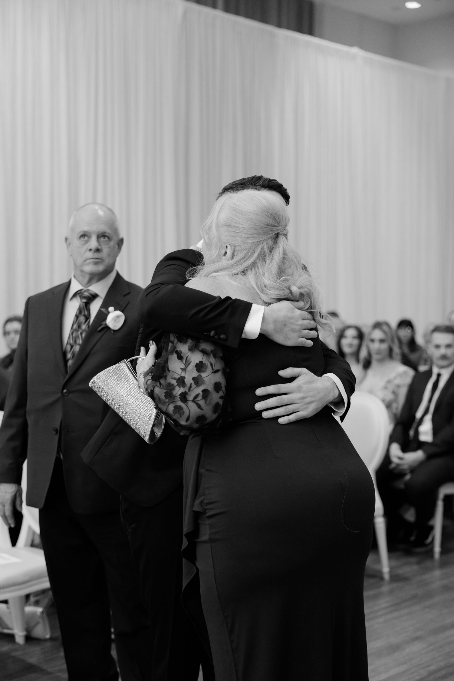 Emotional black and white photograph capturing an embrace during a wedding ceremony.