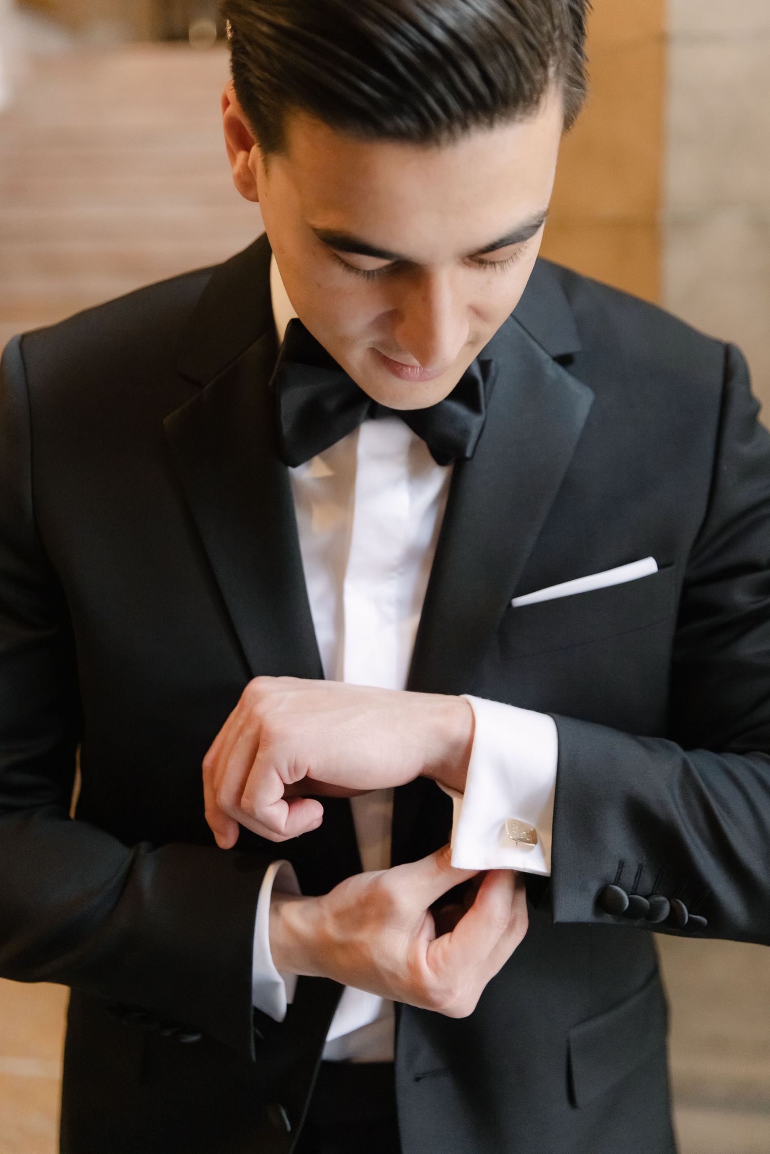 Close-up shot of formal attire with focus on adjusting crisp white cuffs and bowtie.