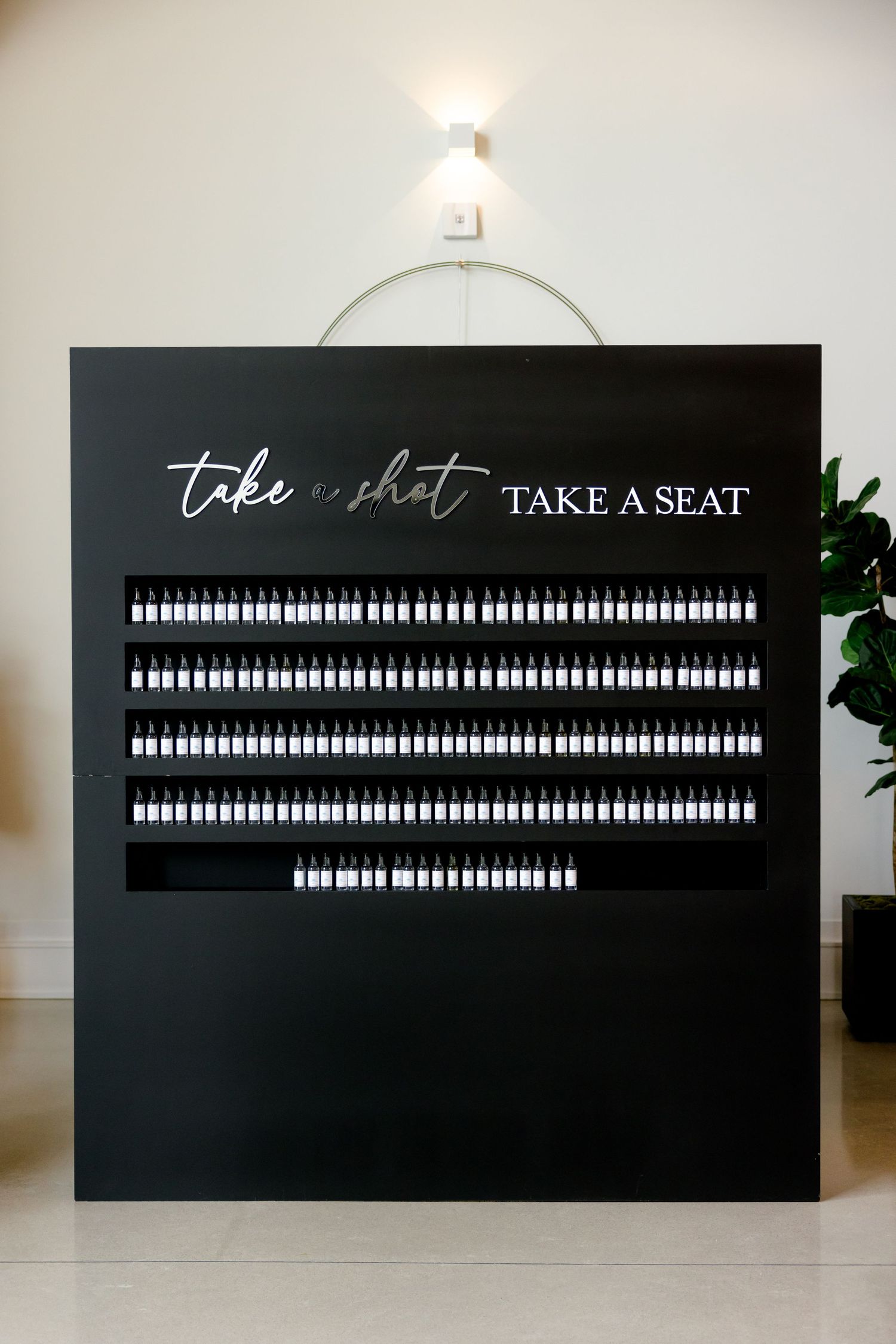 Modern black seating chart display with white text and bottle icons for wedding guests.