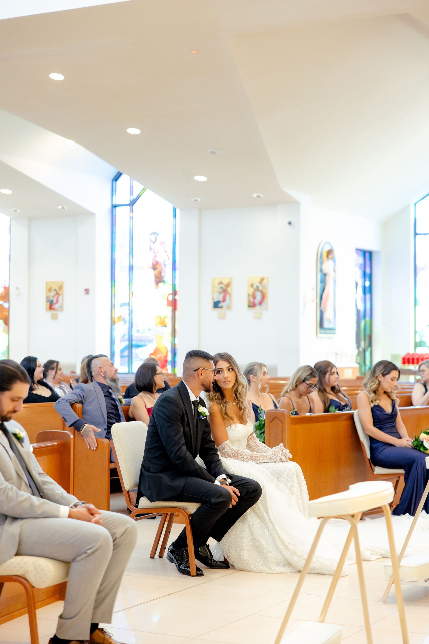 Wedding guests seated in wooden pews during a bright modern church ceremony.
