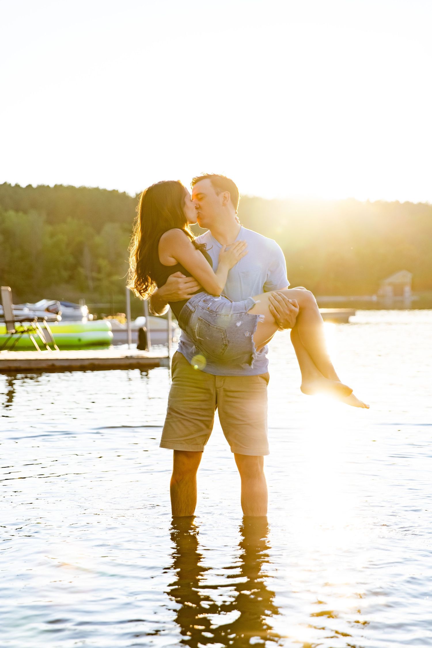 Couple sharing an intimate moment in shallow lake water during golden hour.