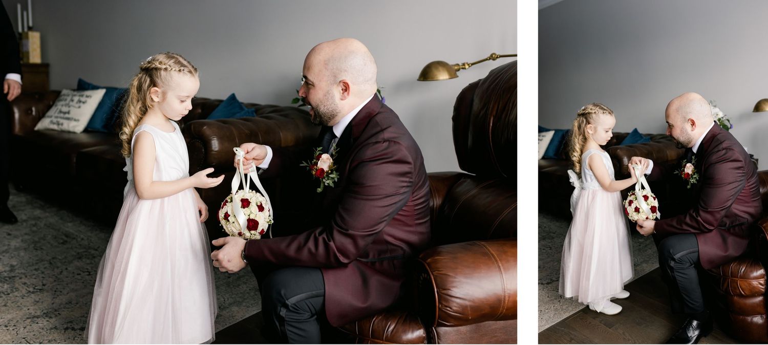 Young flower girl in white dress holding teddy bear with man in burgundy suit.