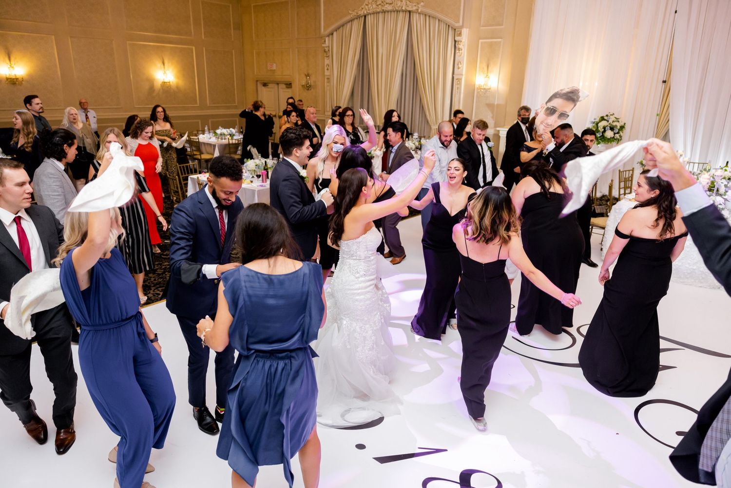 Wedding reception dance floor filled with guests dancing and celebrating in an elegant ballroom.