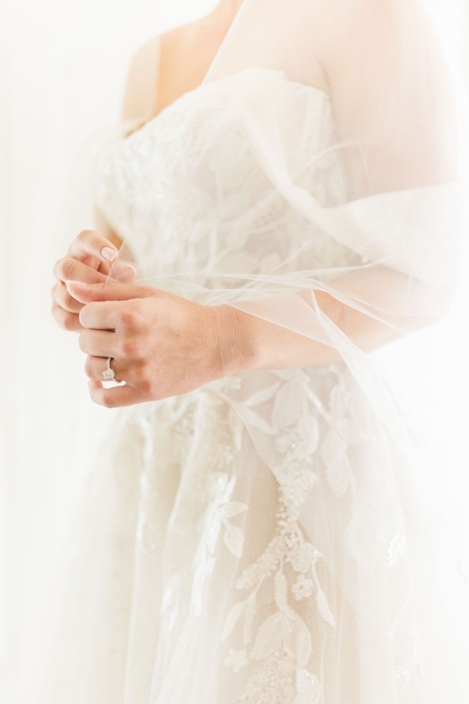 Ethereal detail of delicate lace wedding dress in soft natural light.