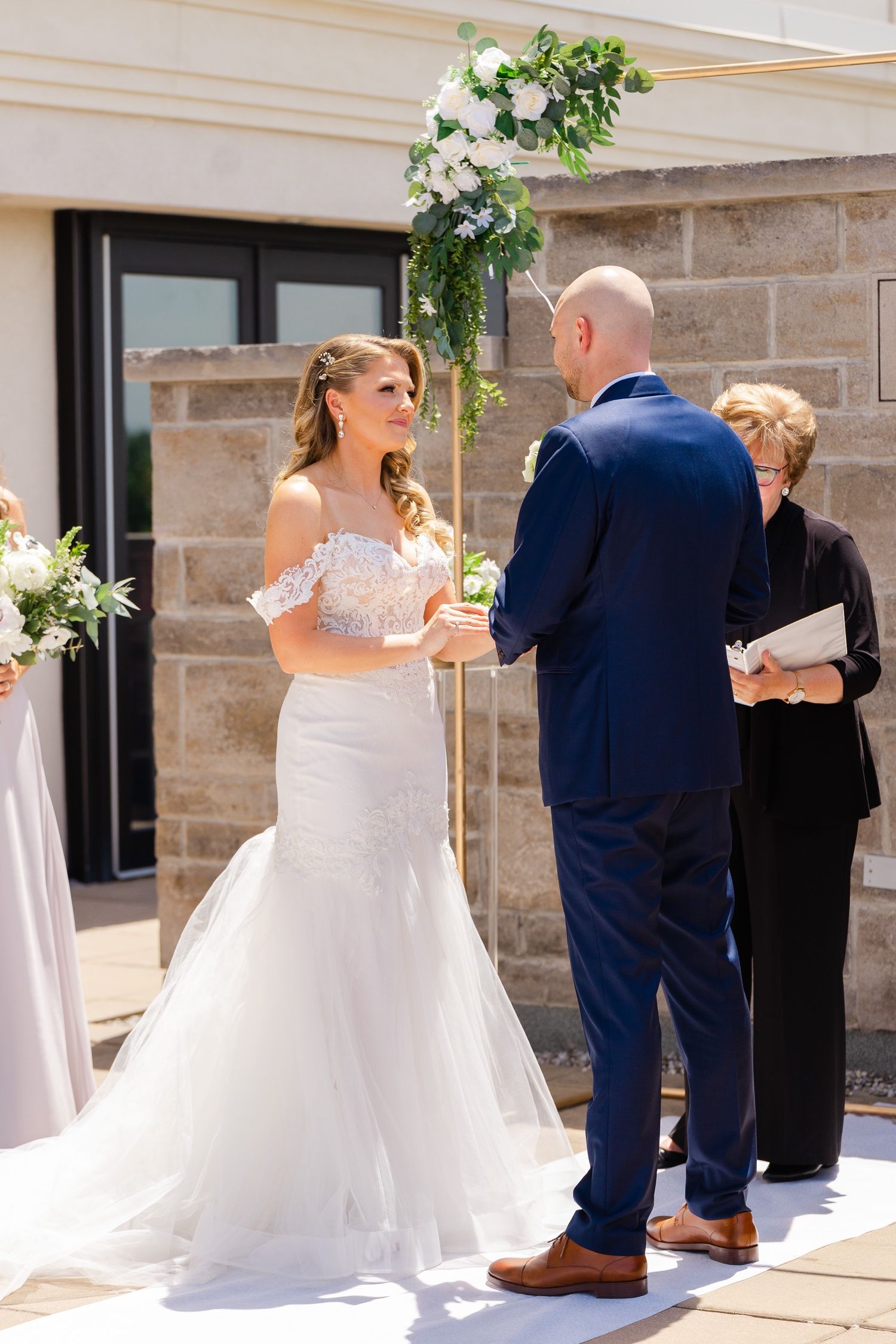 A joyful wedding ceremony moment captured on an outdoor terrace with stone walls and floral decorations.