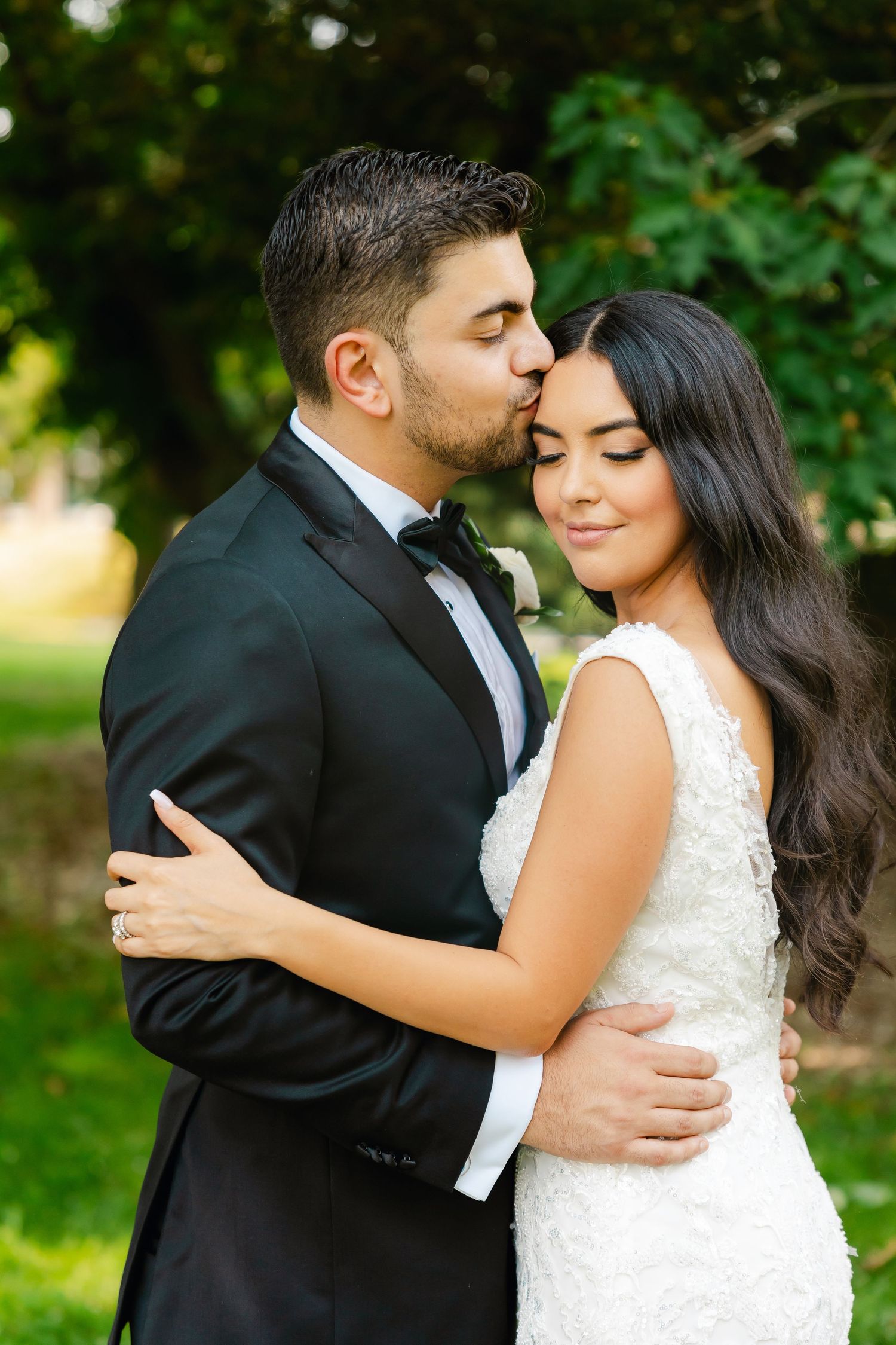 Romantic wedding portrait of couple embracing in a garden with soft natural lighting.