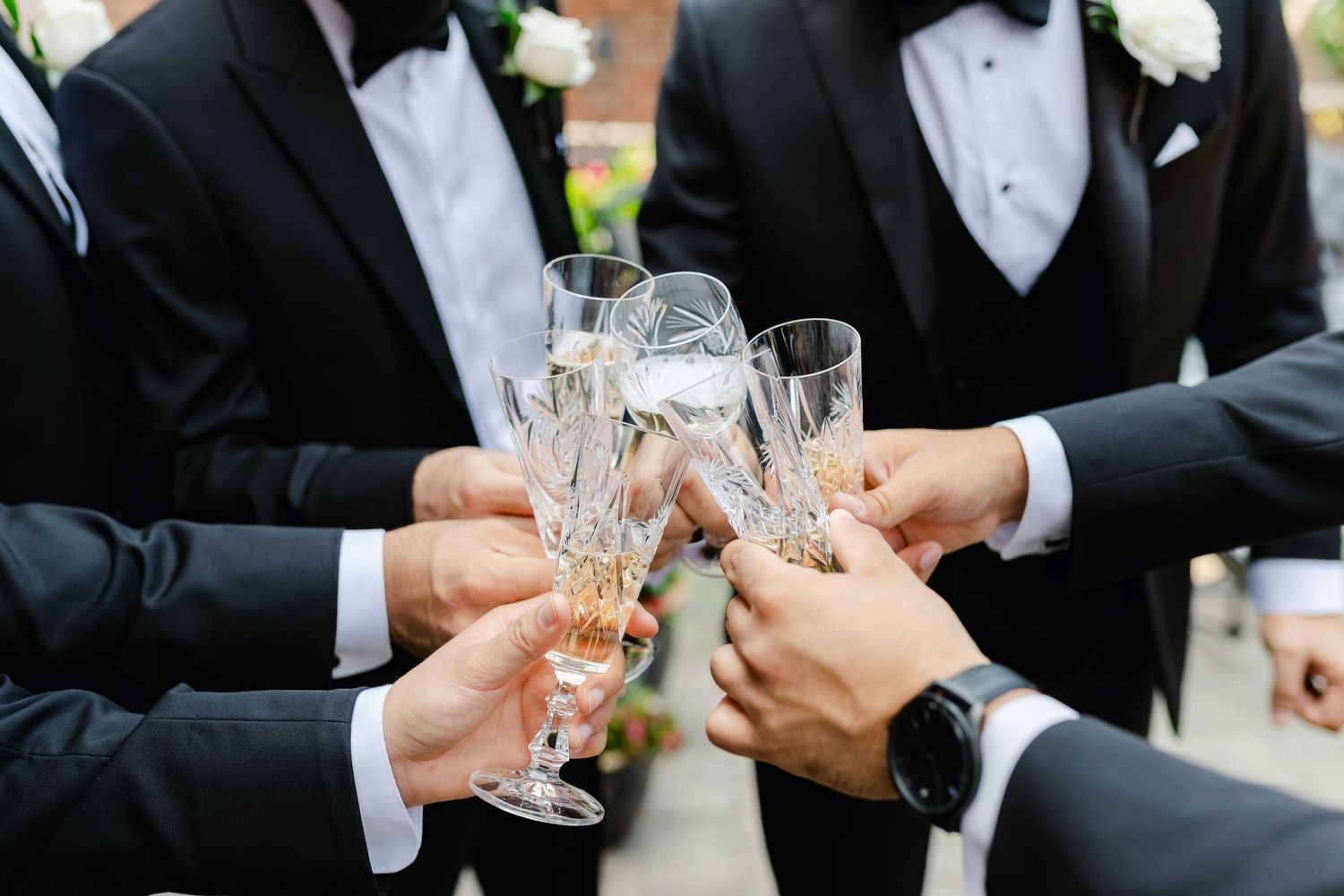 Crystal champagne glasses clinking in celebration at a formal wedding event.