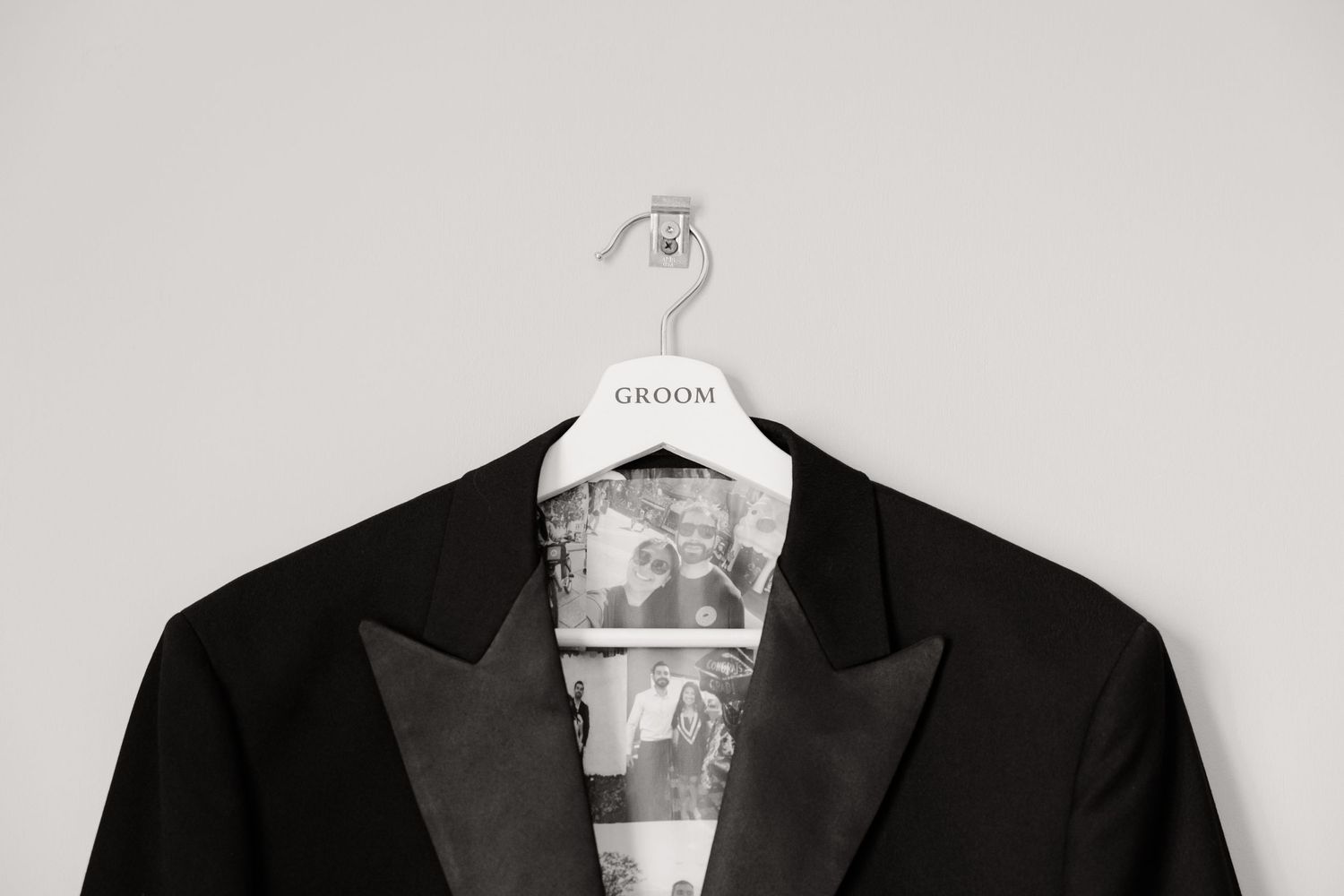 Black and white detail shot of a tuxedo jacket on a branded hanger.