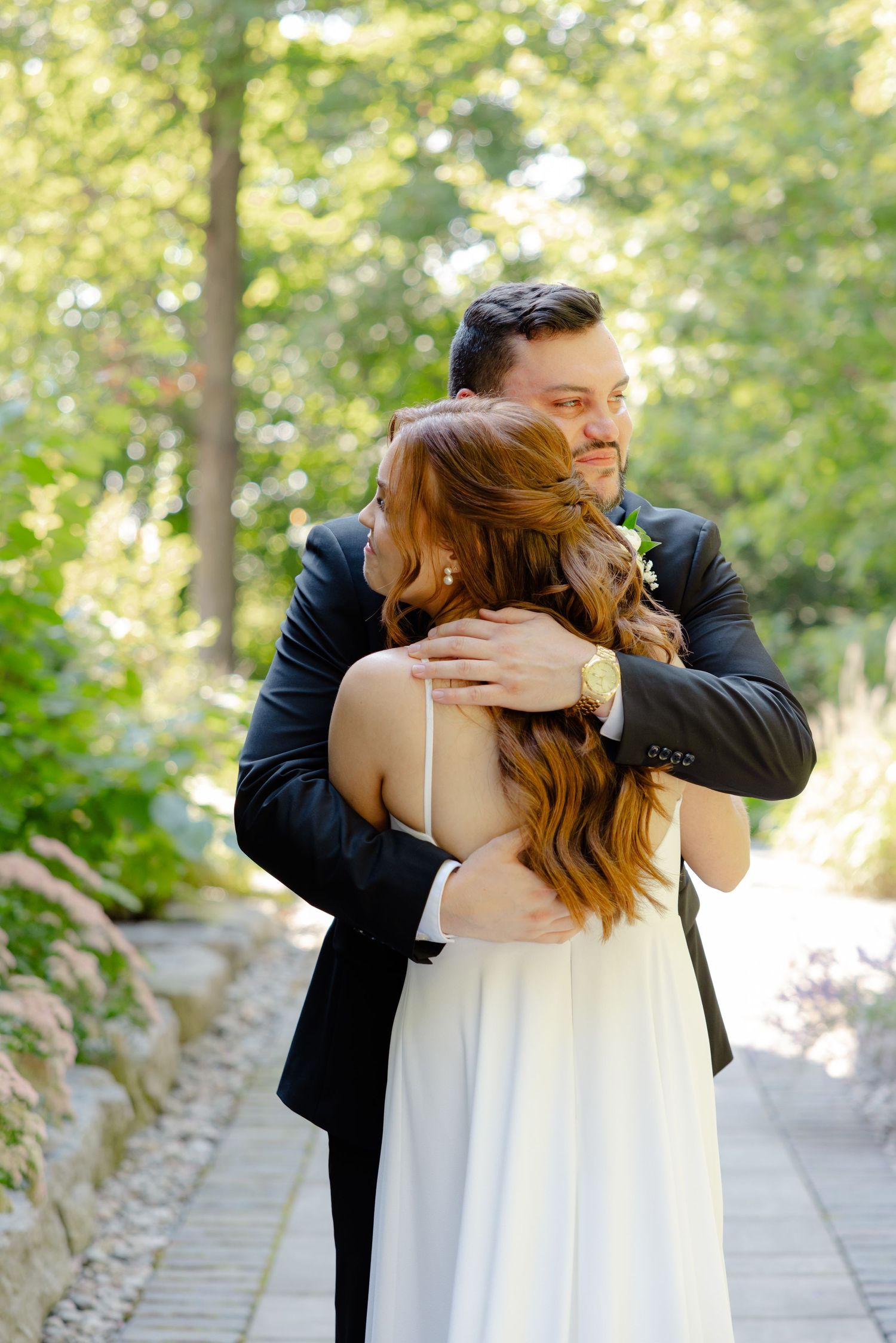 A romantic wedding moment captured in a sun-dappled garden setting with decorative railing.