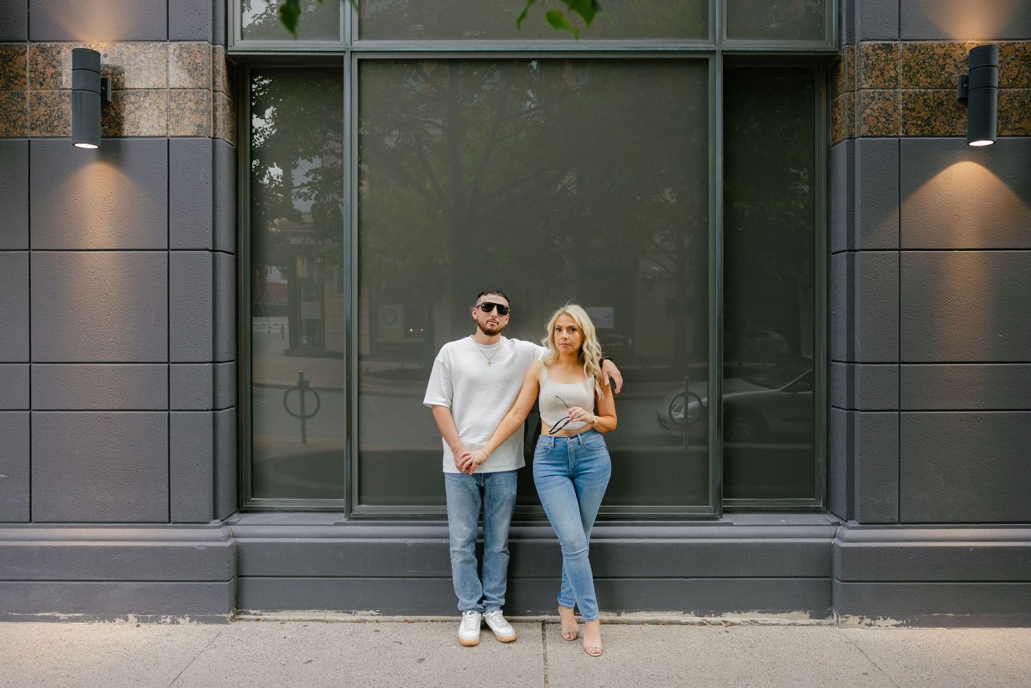 Casual street style portrait of couple standing together against modern architecture.