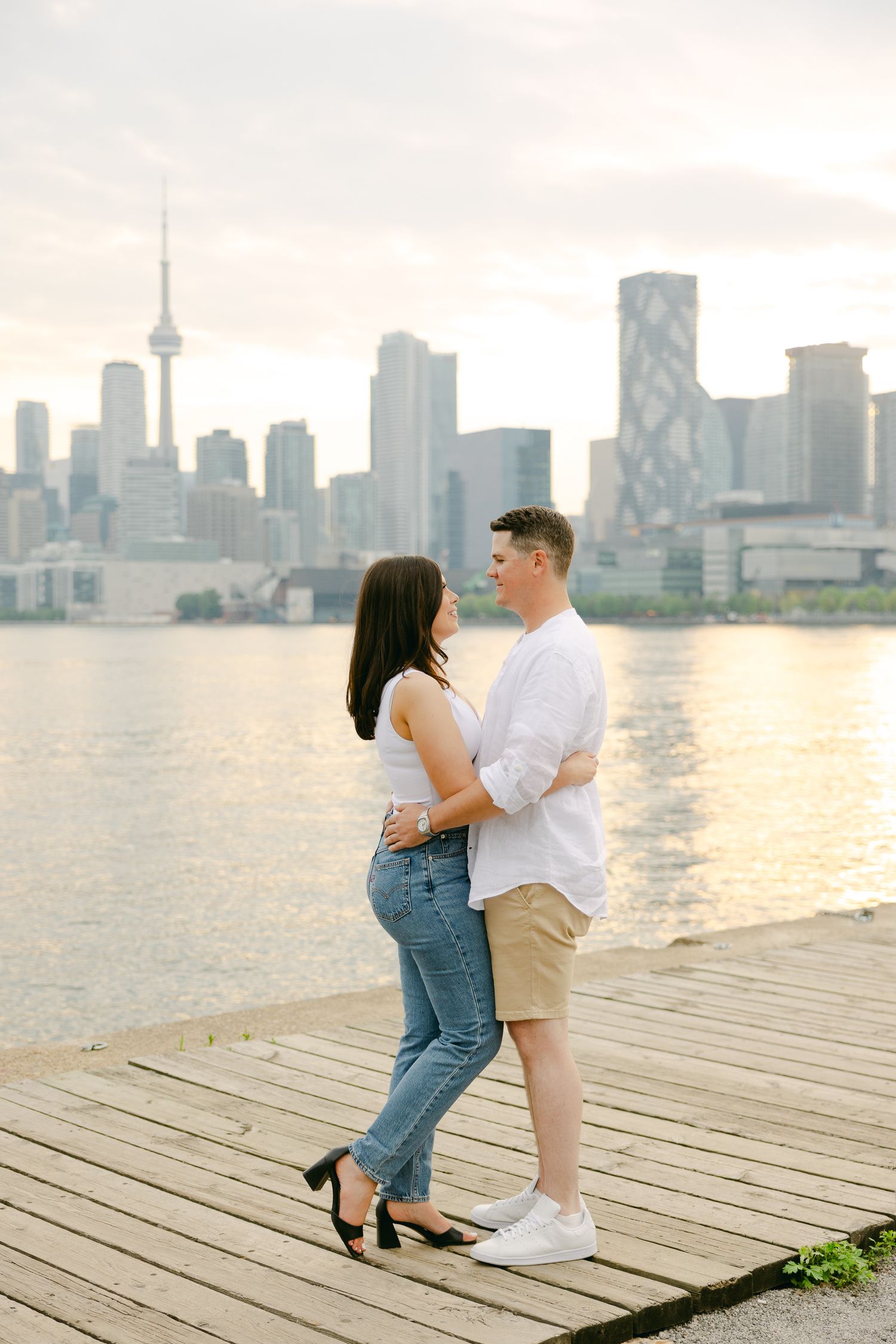 Sunset embrace on waterfront pier with Toronto's iconic skyline in background.