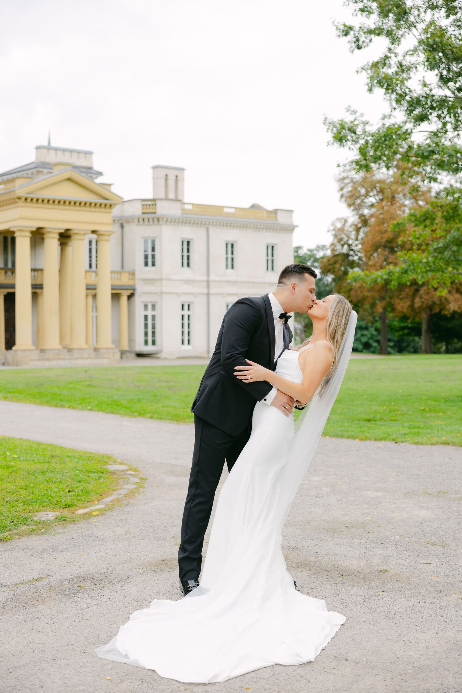 Couple shares romantic moment outside elegant historic building with columns.