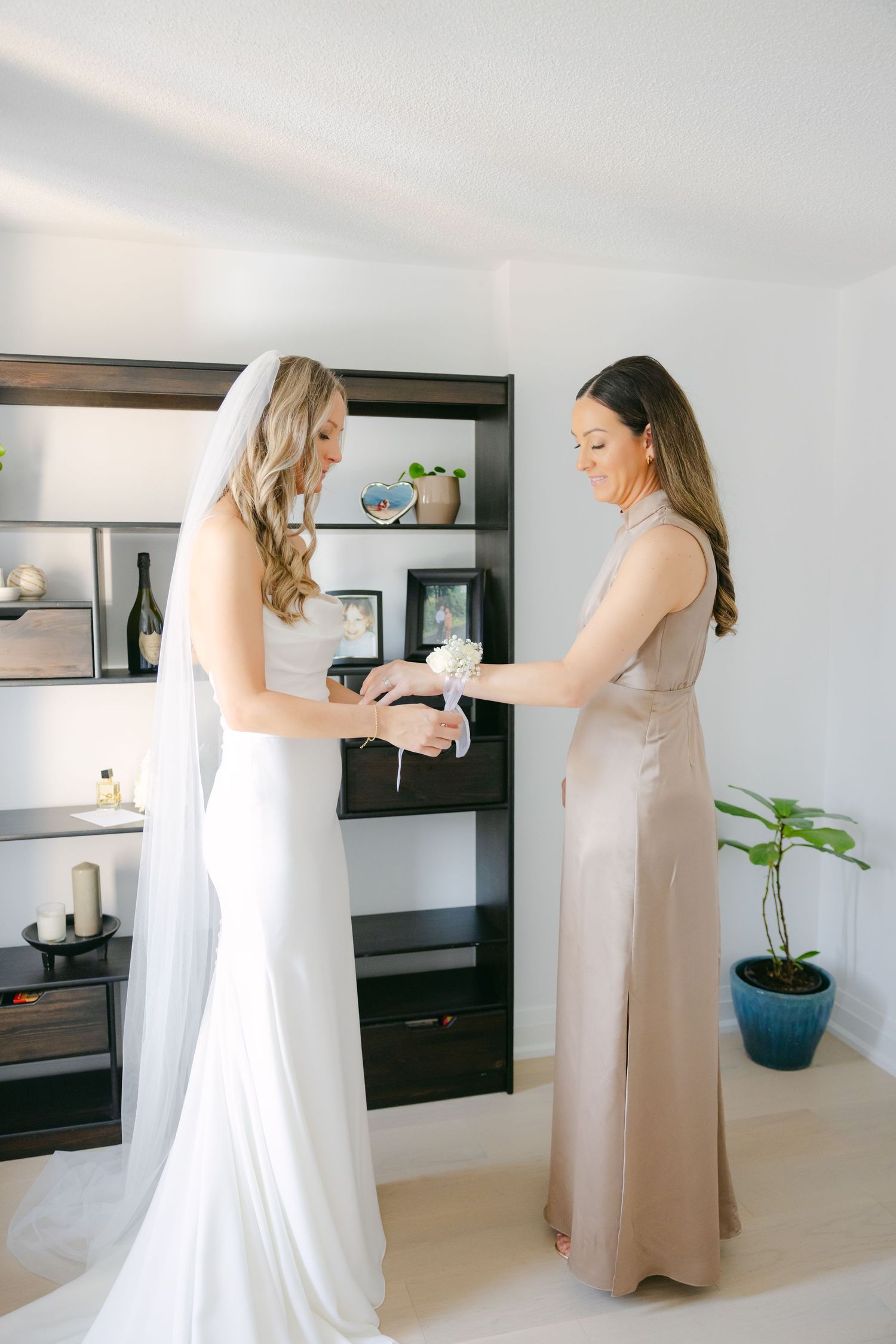 Final wedding preparations take place in a bright room with modern decor and shelving.