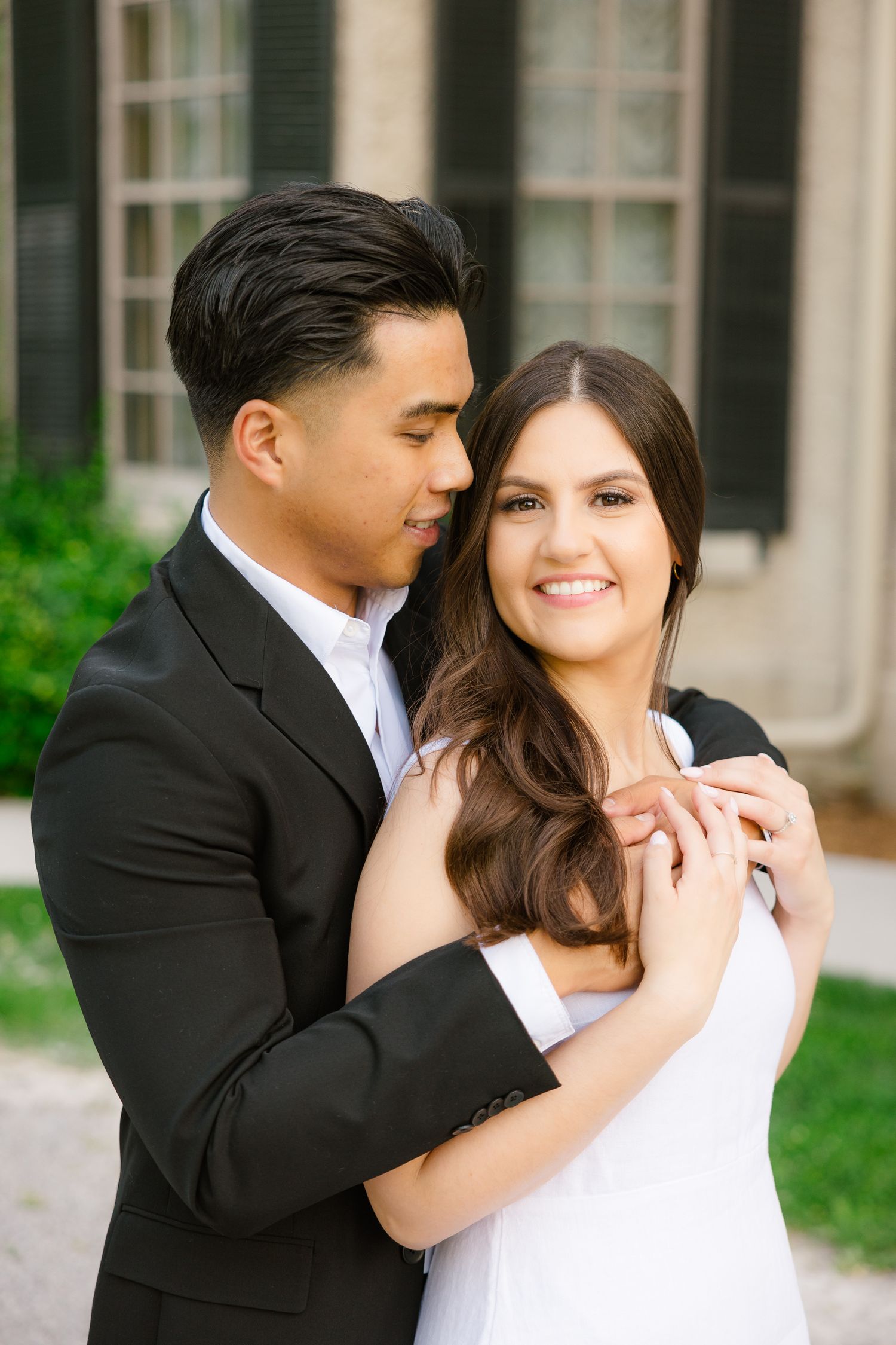 Couple in formal wear shares romantic moment in front of historic building.