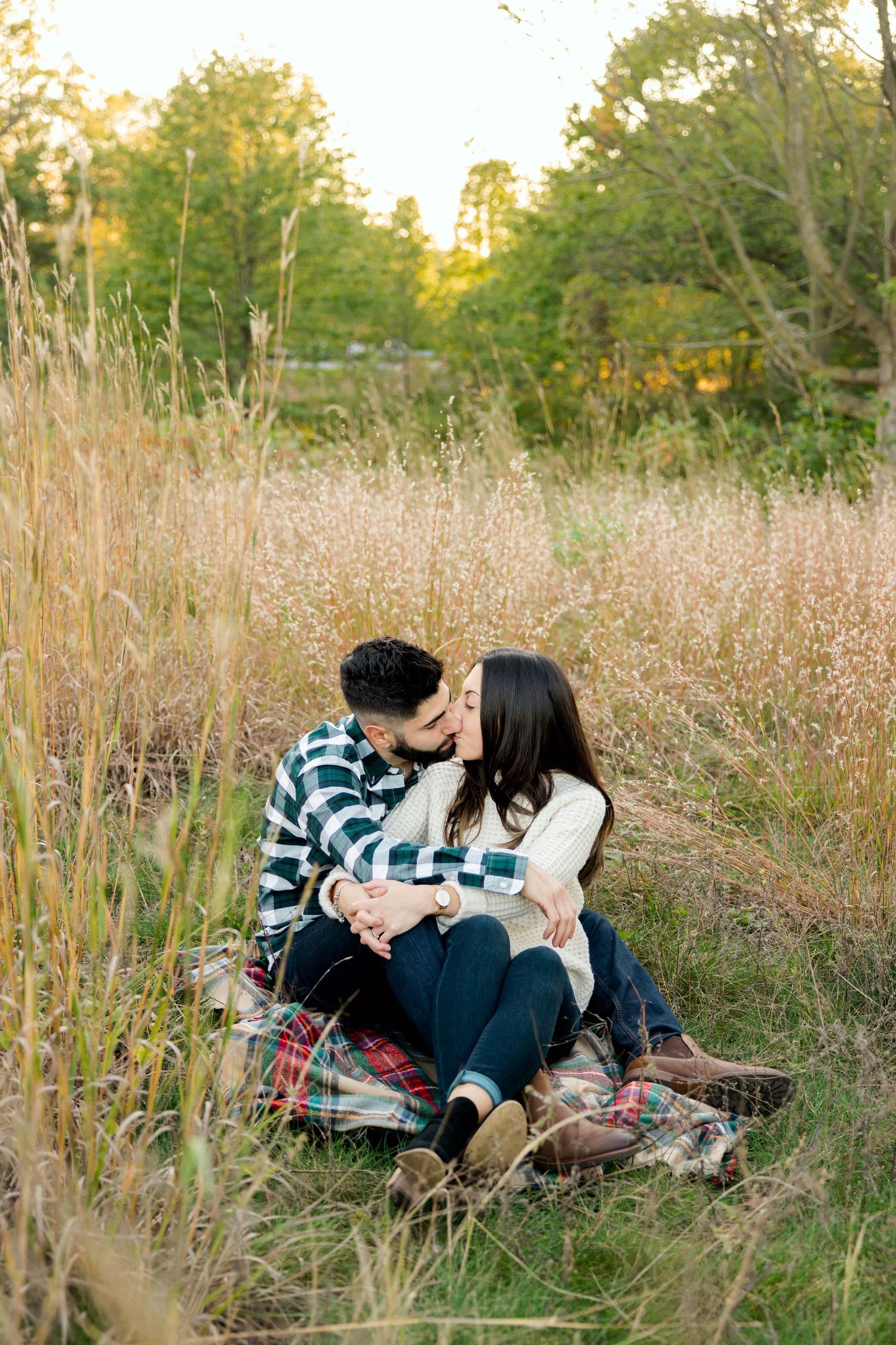 Intimate portrait of couple sharing romantic moment on plaid blanket in autumn field.