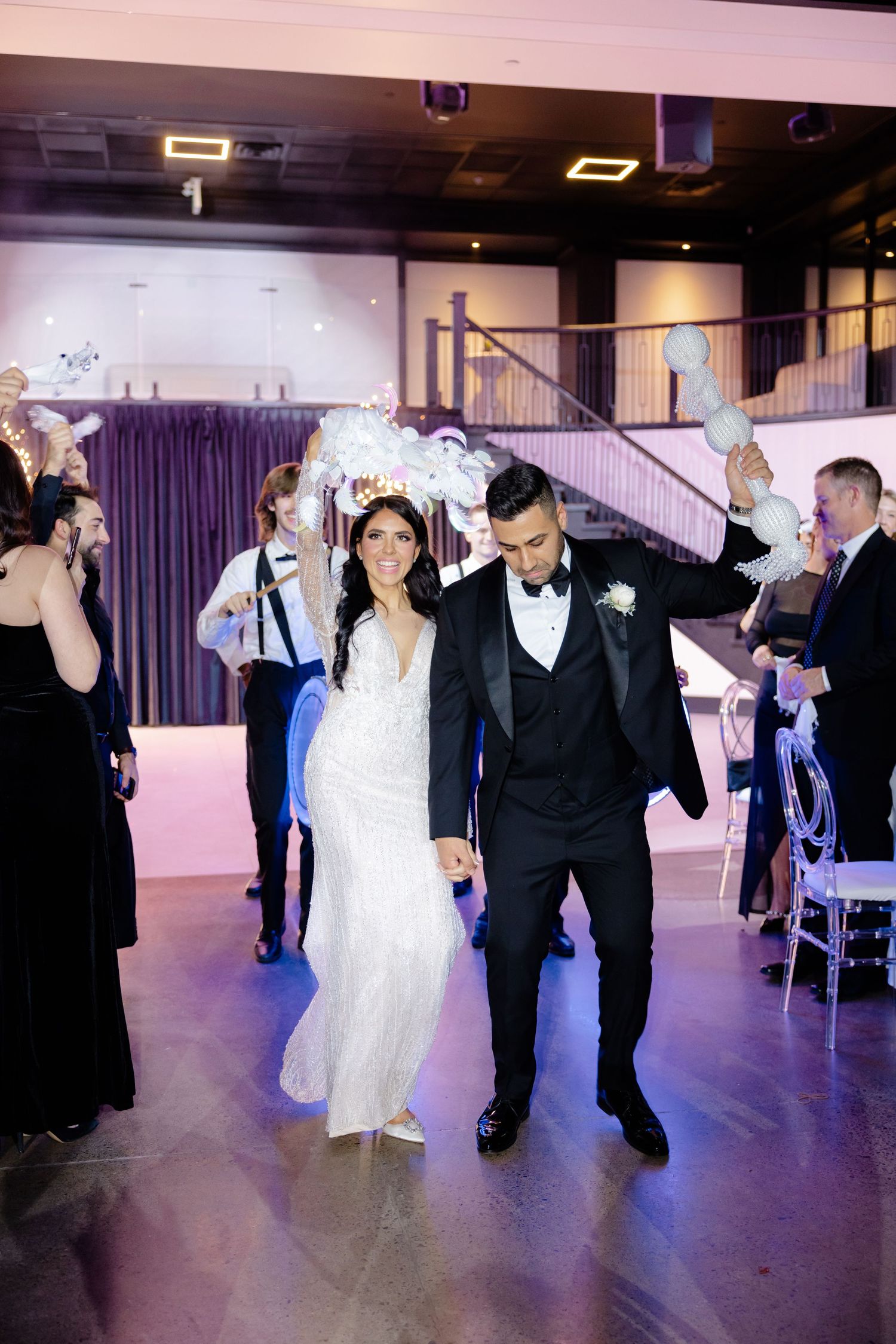 Celebratory wedding exit with guests cheering in an elegantly decorated venue space.