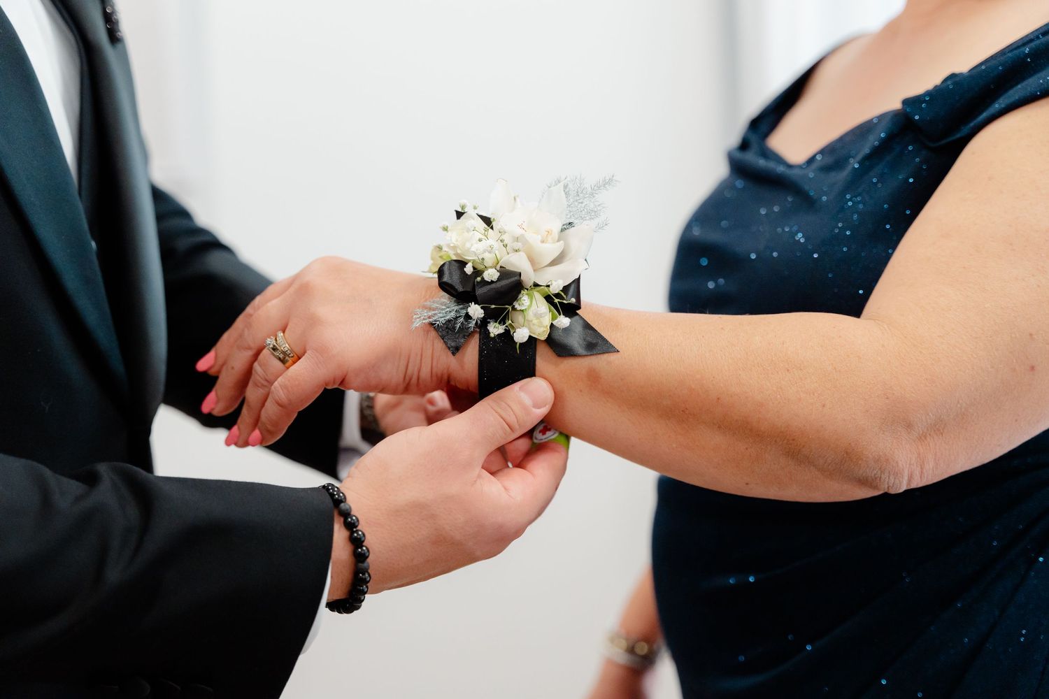 A close-up of hands pinning a white floral corsage during a wedding ceremony.