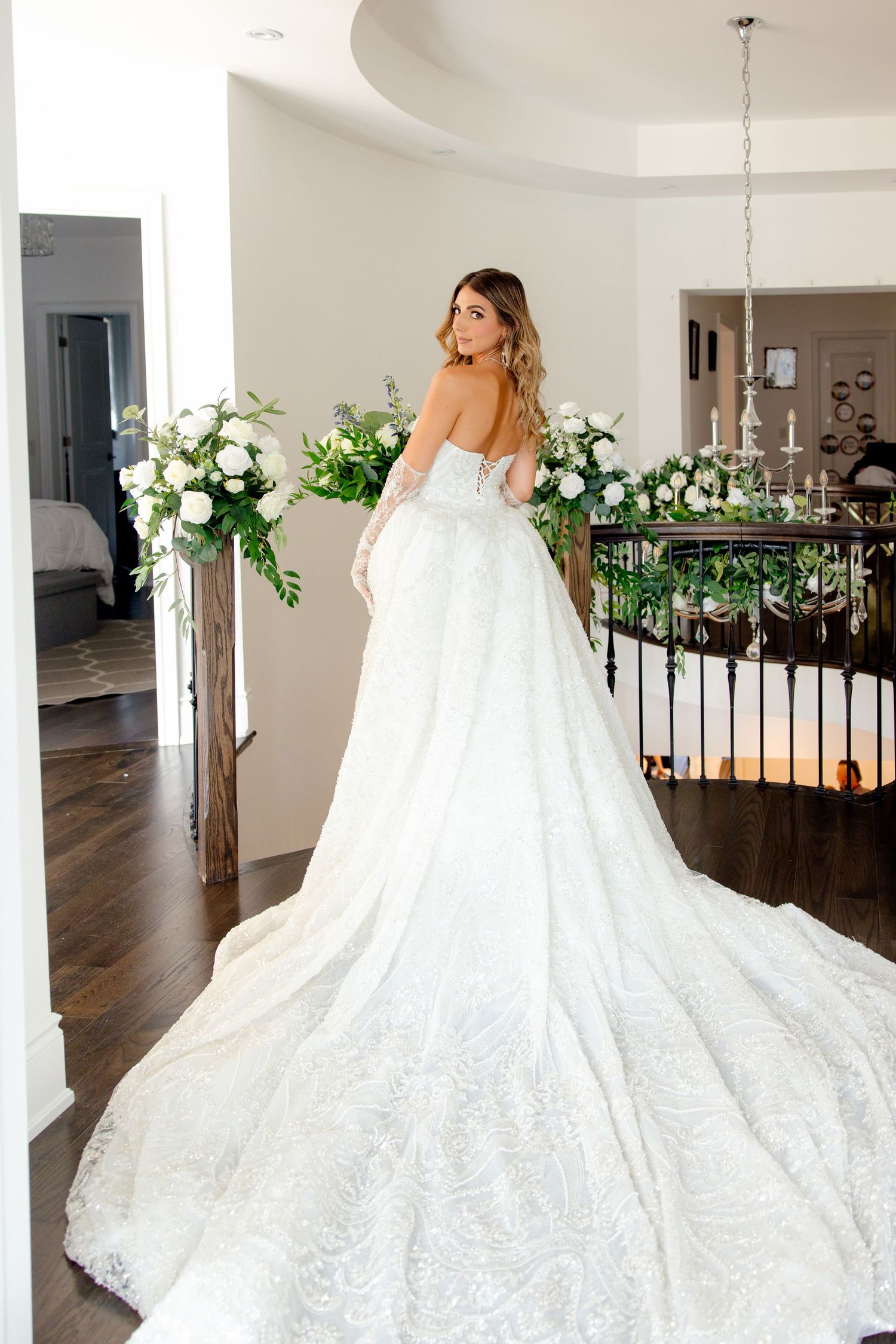 Stunning cathedral train wedding dress photographed from behind in a modern interior setting.