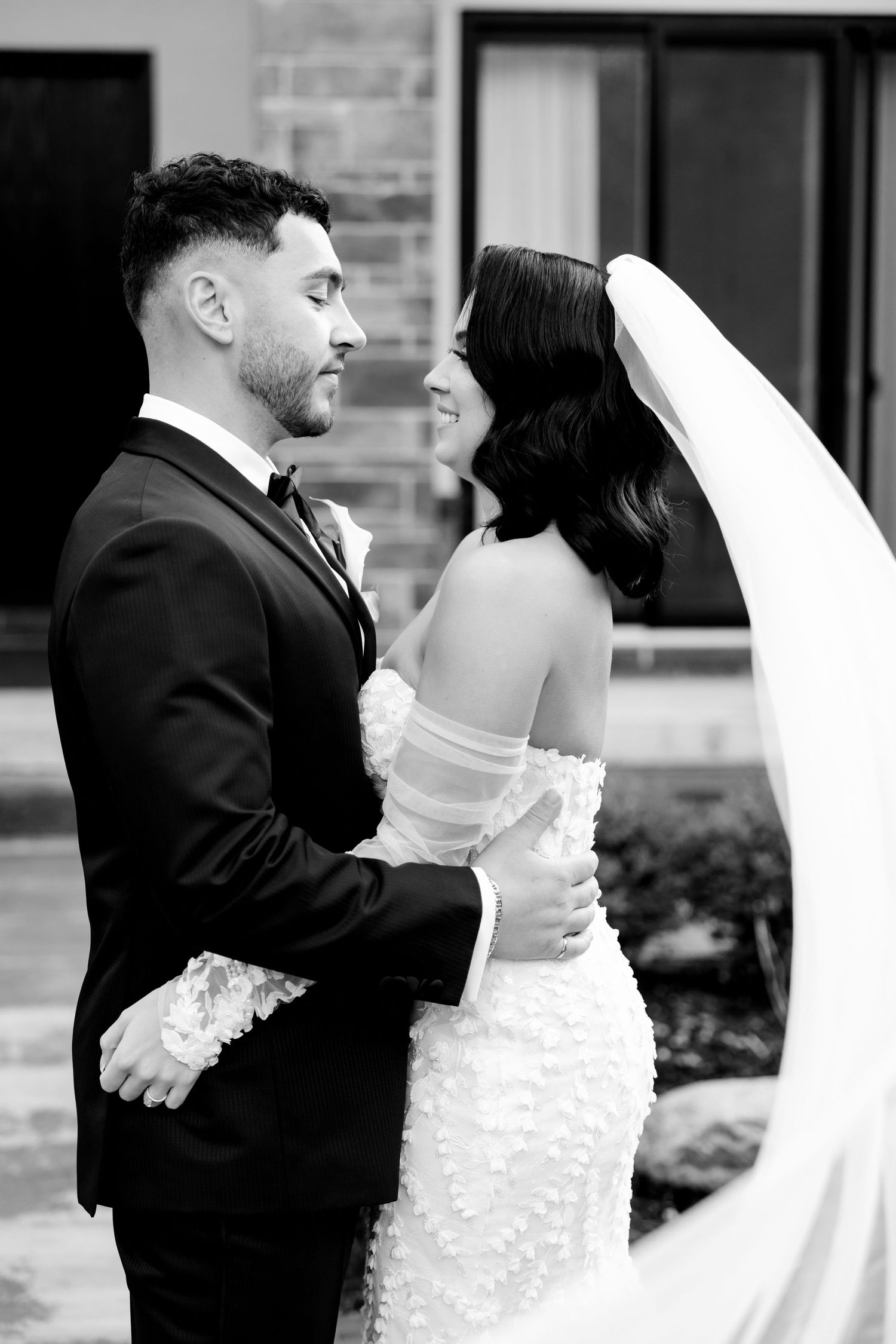 A black and white intimate moment between newlyweds showcasing classic wedding fashion.
