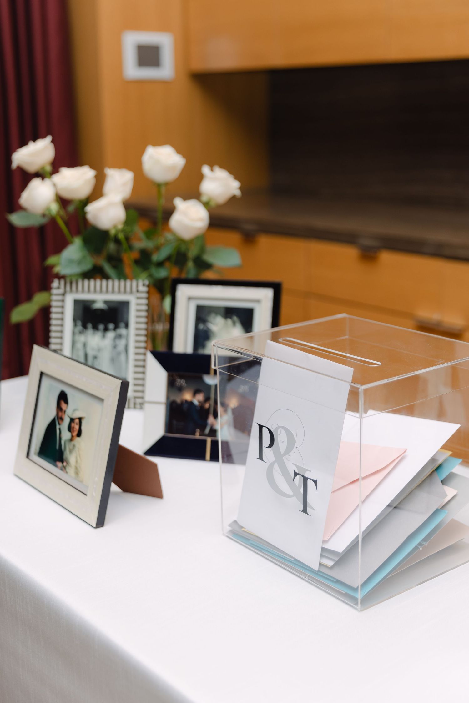 Elegant wedding photo display with white roses and framed pictures on a table with acrylic box.