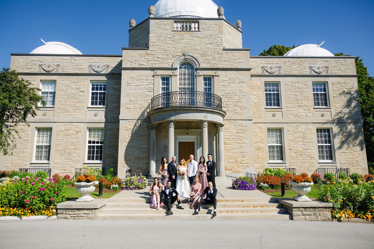 Wedding group photo taken in front of grand historic building with dome and columns.