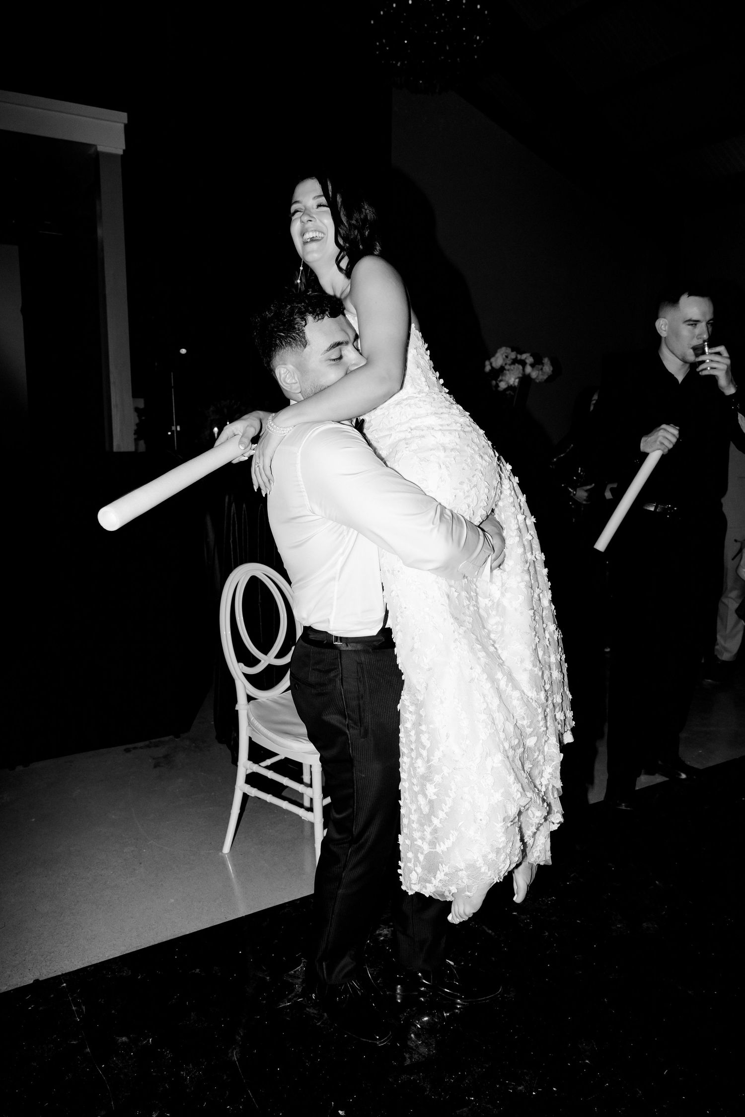 A romantic dance lift moment at wedding reception captured in black and white photography.
