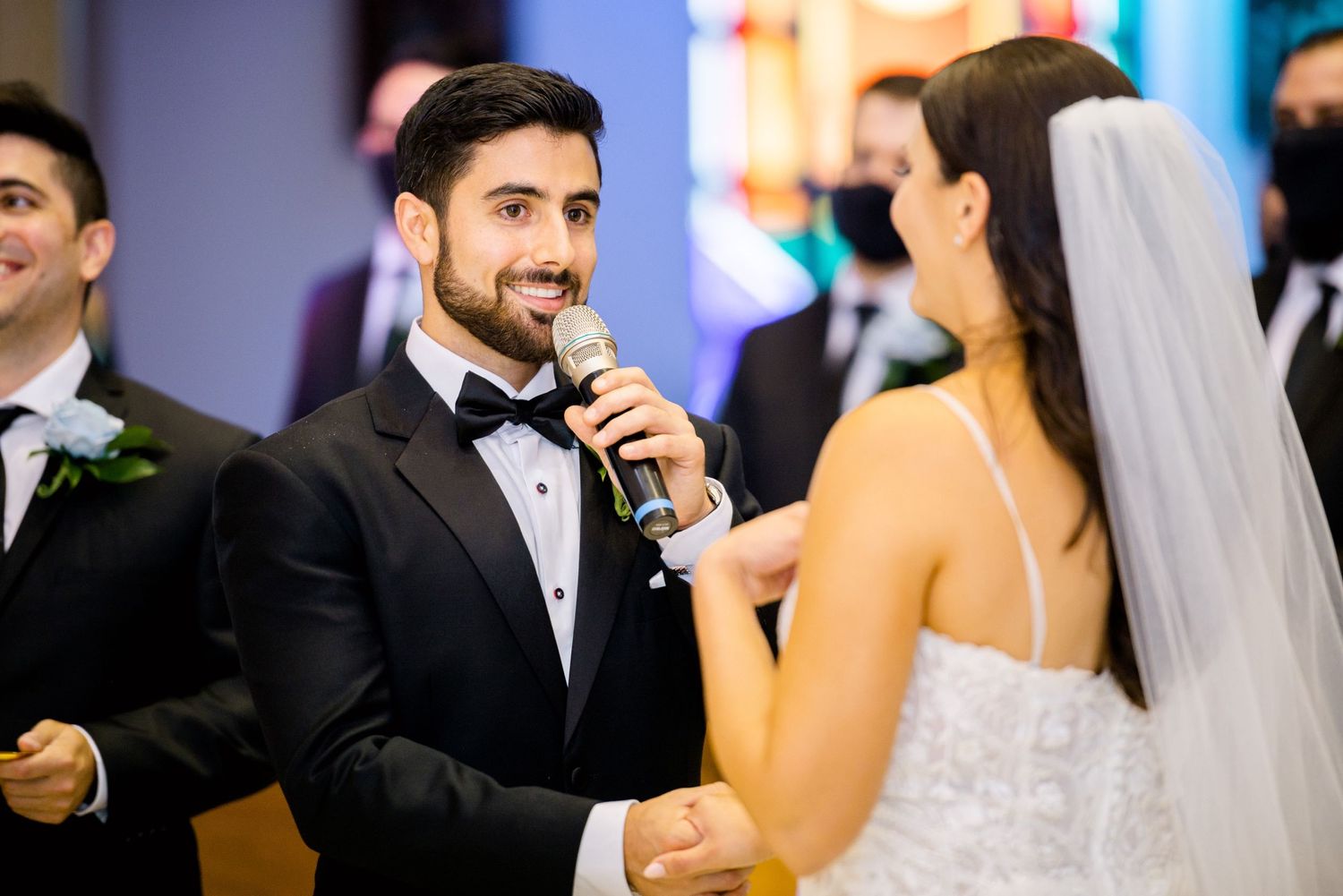 A couple shares a joyful moment during their wedding reception as the groom speaks into a microphone.