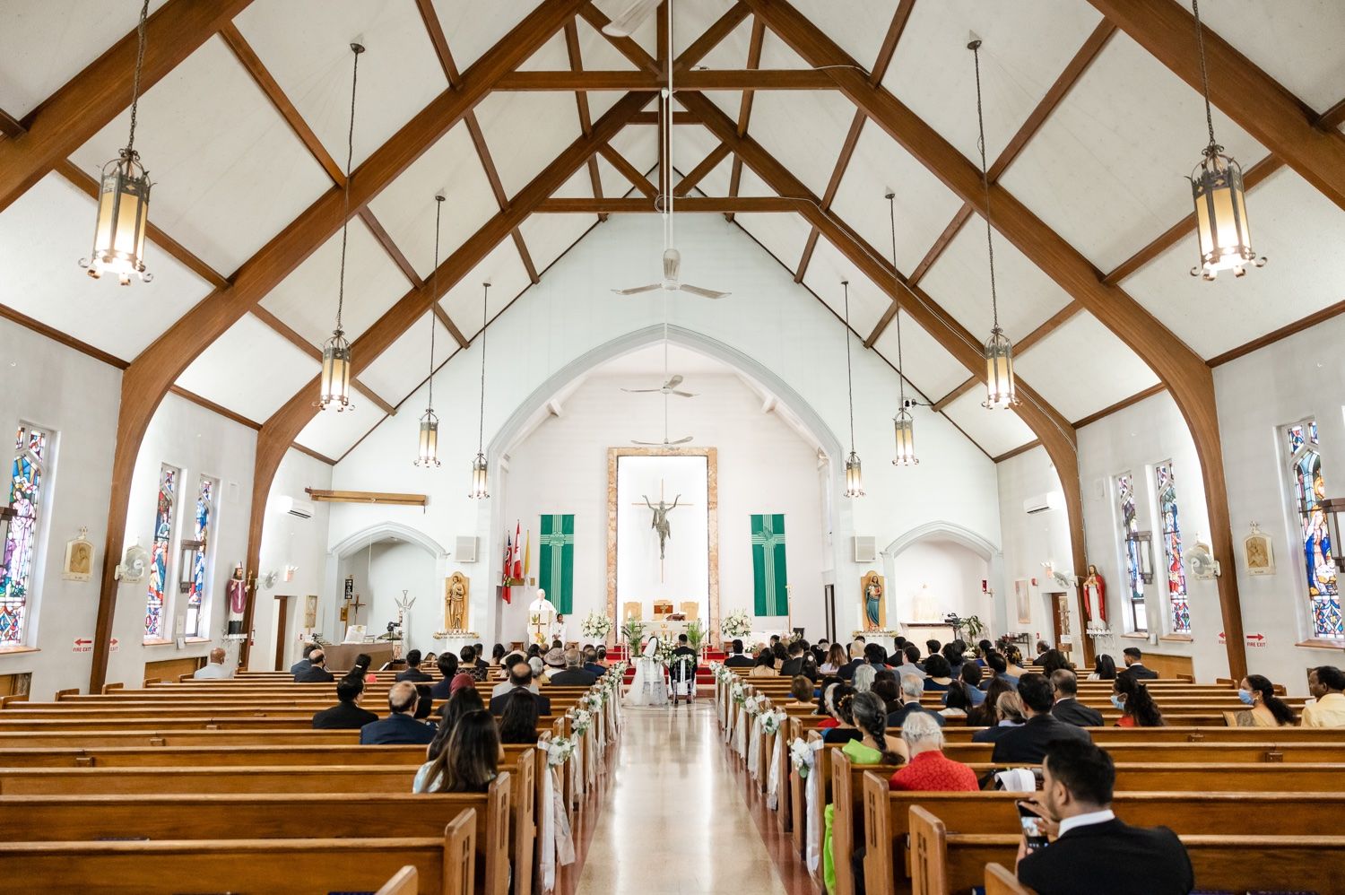 A church wedding ceremony venue with exposed wooden beams and vaulted ceilings filled with seated guests.