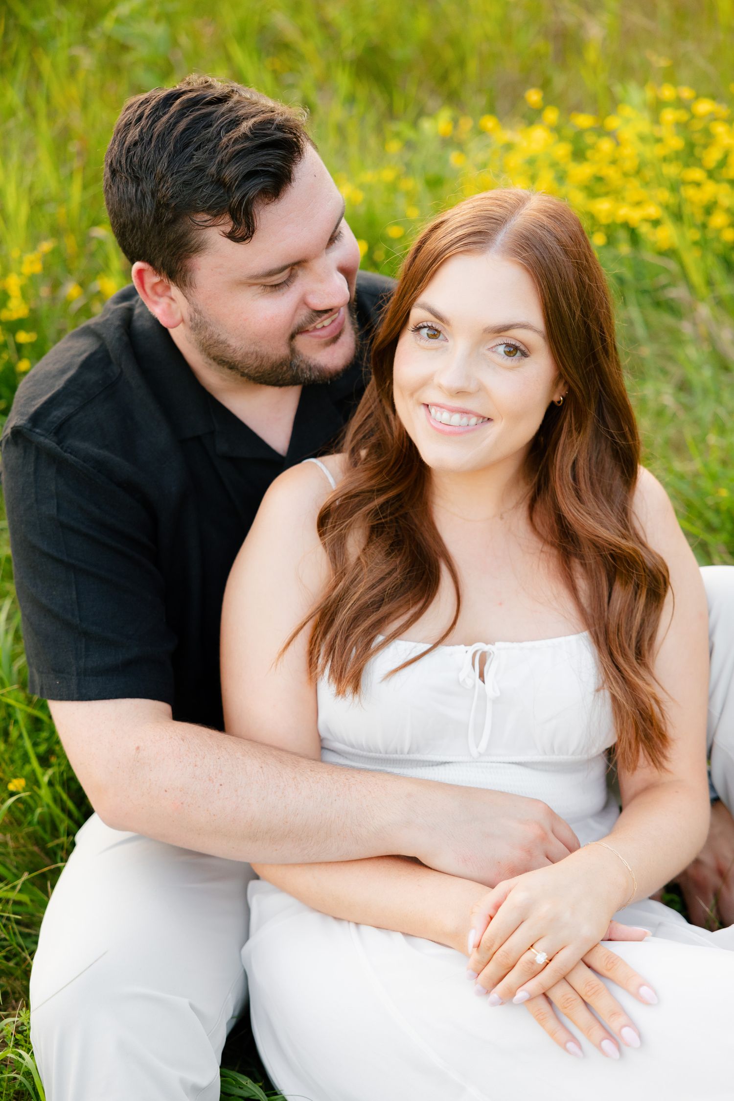 Close-up portrait of couple in casual attire against green summer meadow.