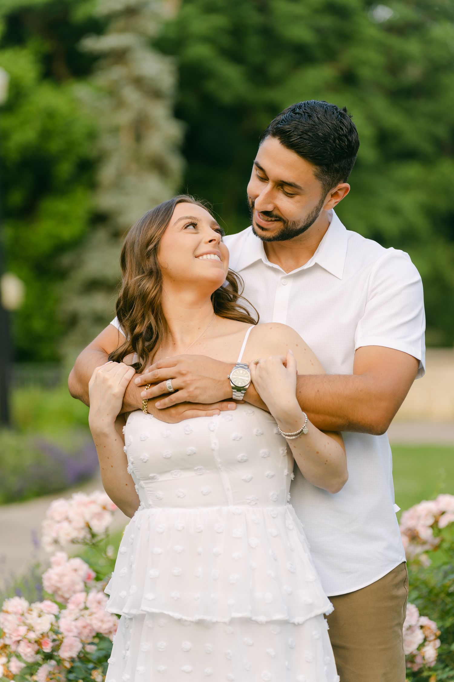 A tender moment captured between a couple against a backdrop of blooming rose bushes.