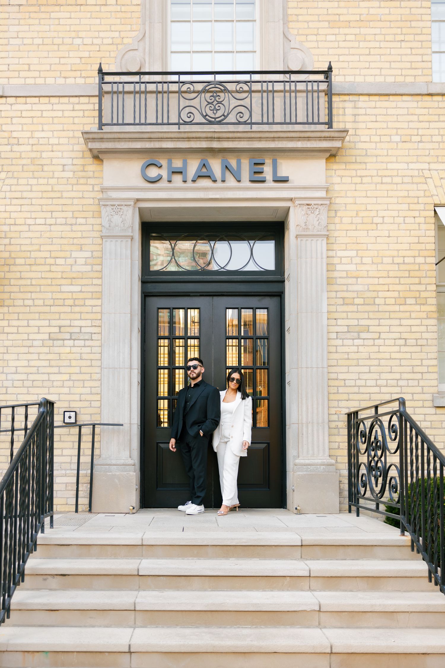 Full length view of couple standing in elegant doorway of Chanel boutique.
