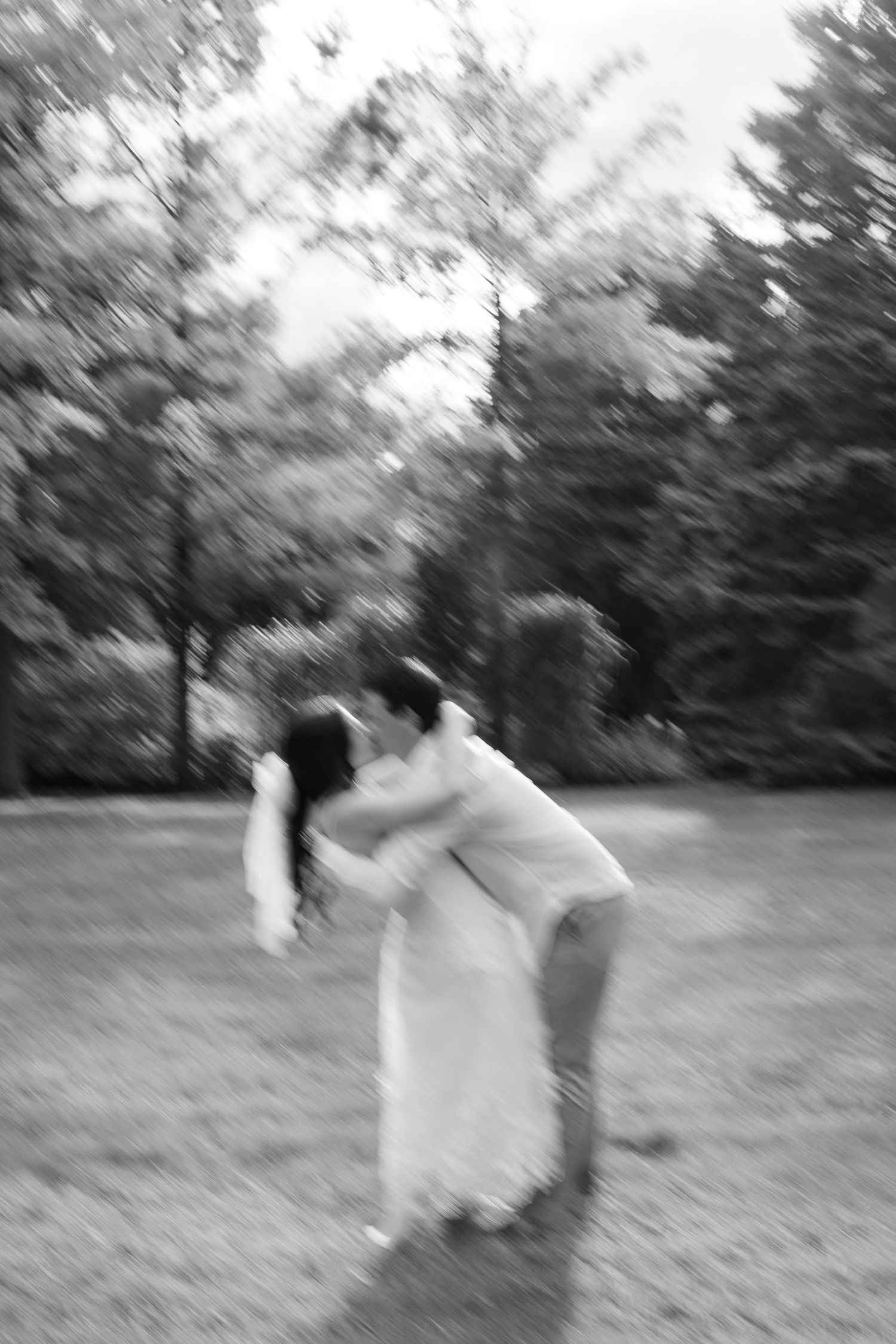 A romantic dance dip captured in black and white against a forest backdrop.