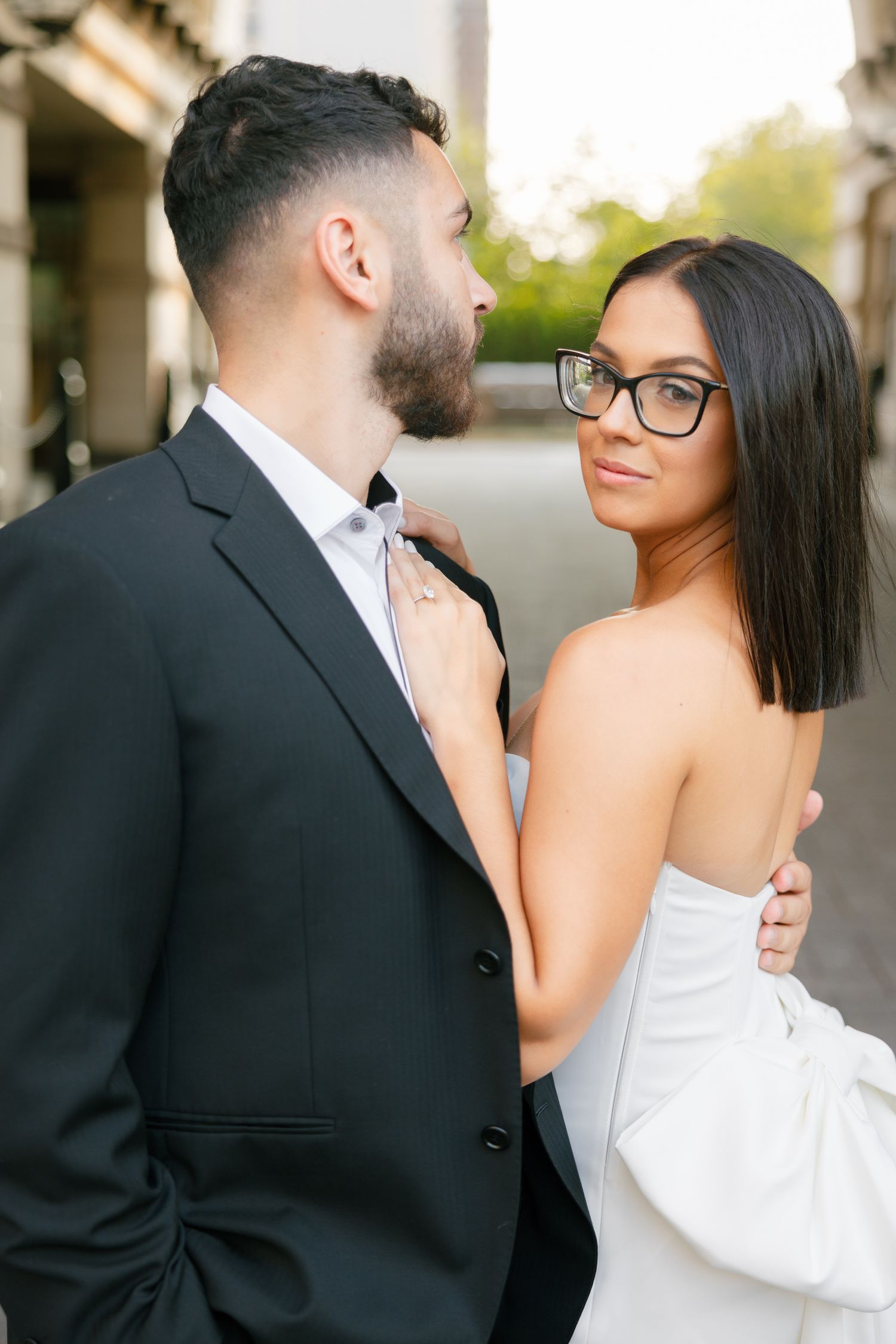 Candid shot of a couple in formal wear sharing an intimate moment in an urban setting.