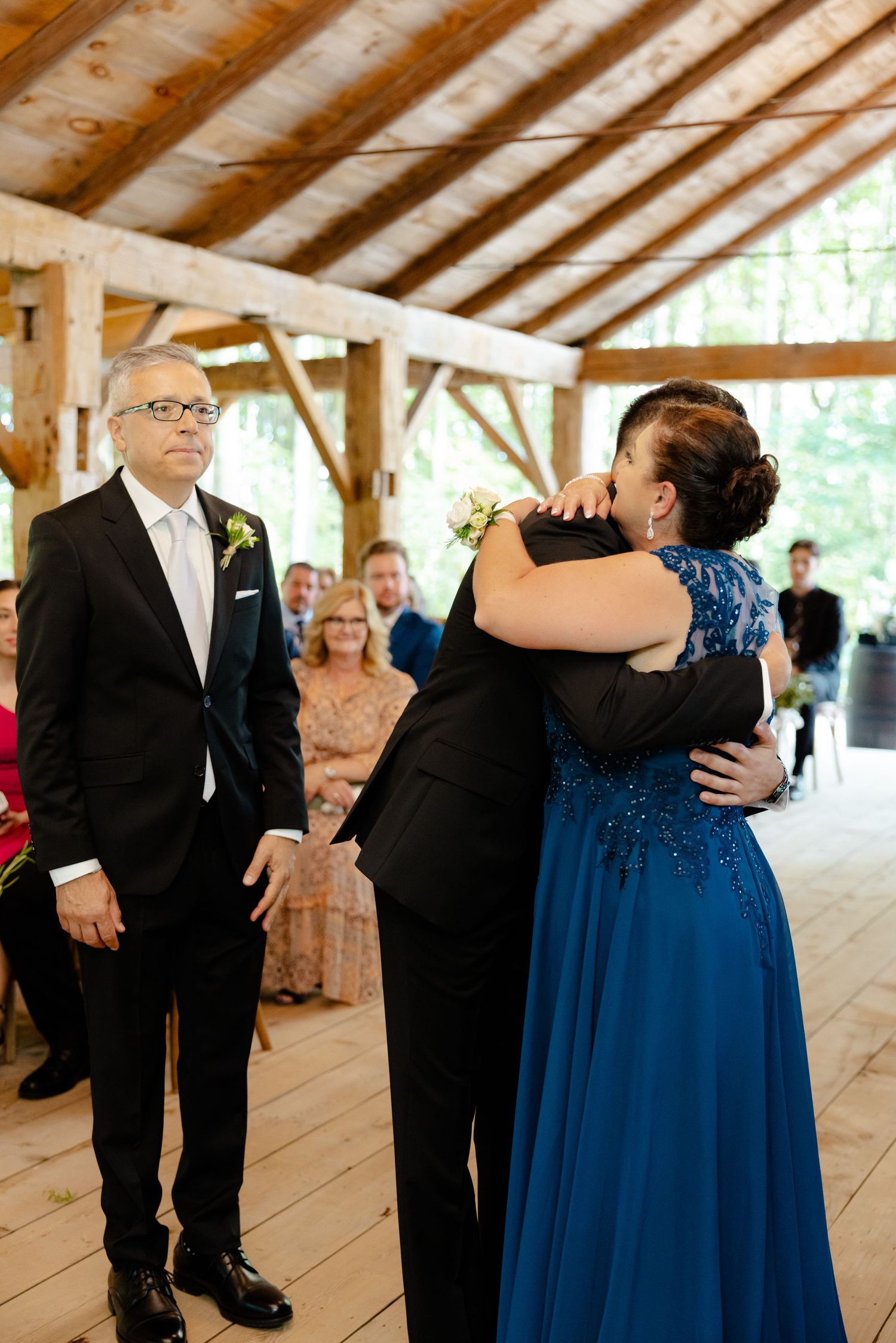 Touching wedding ceremony moment in a rustic wooden pavilion with natural lighting.