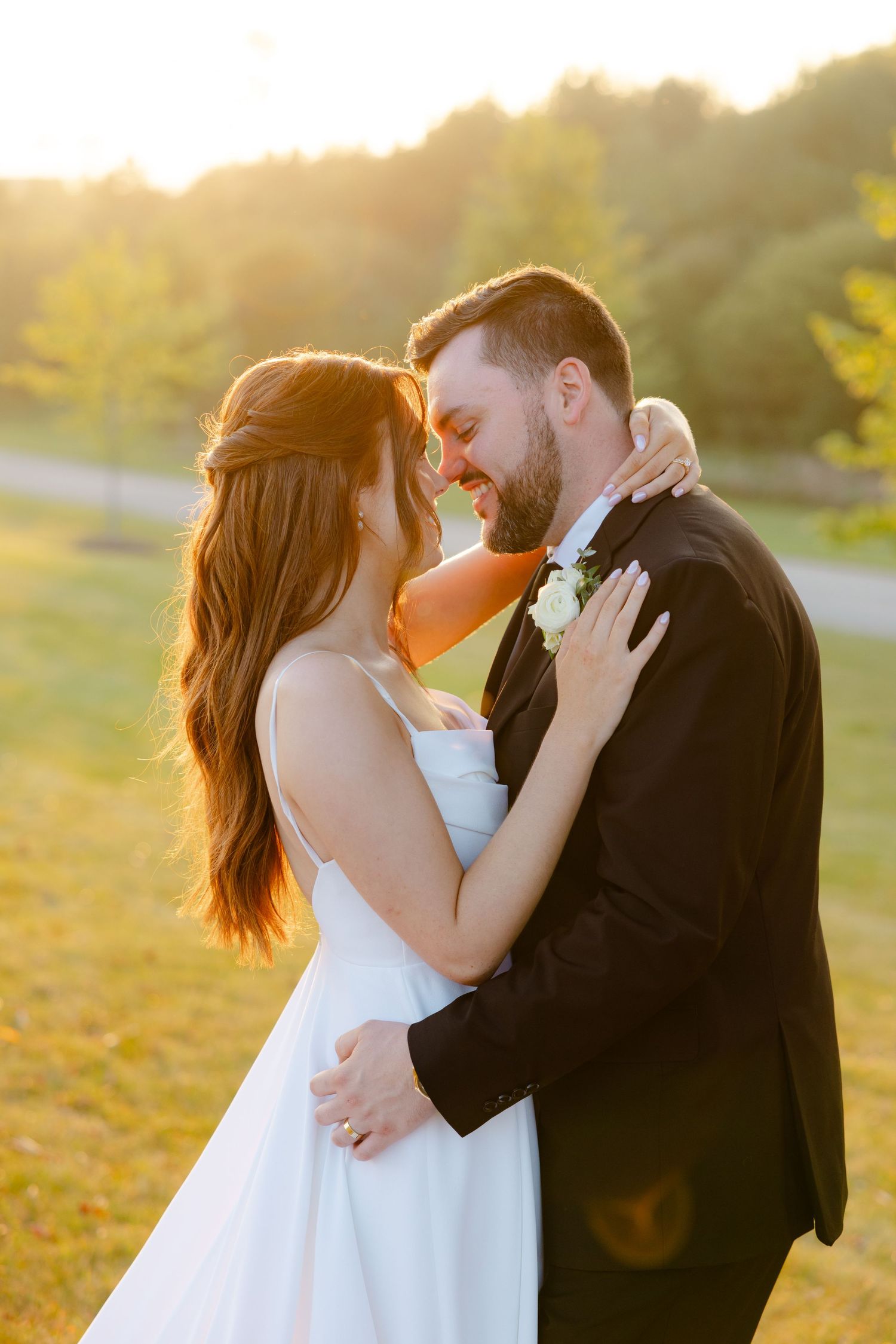 A romantic wedding portrait captures an intimate moment between newlyweds in warm sunset lighting.