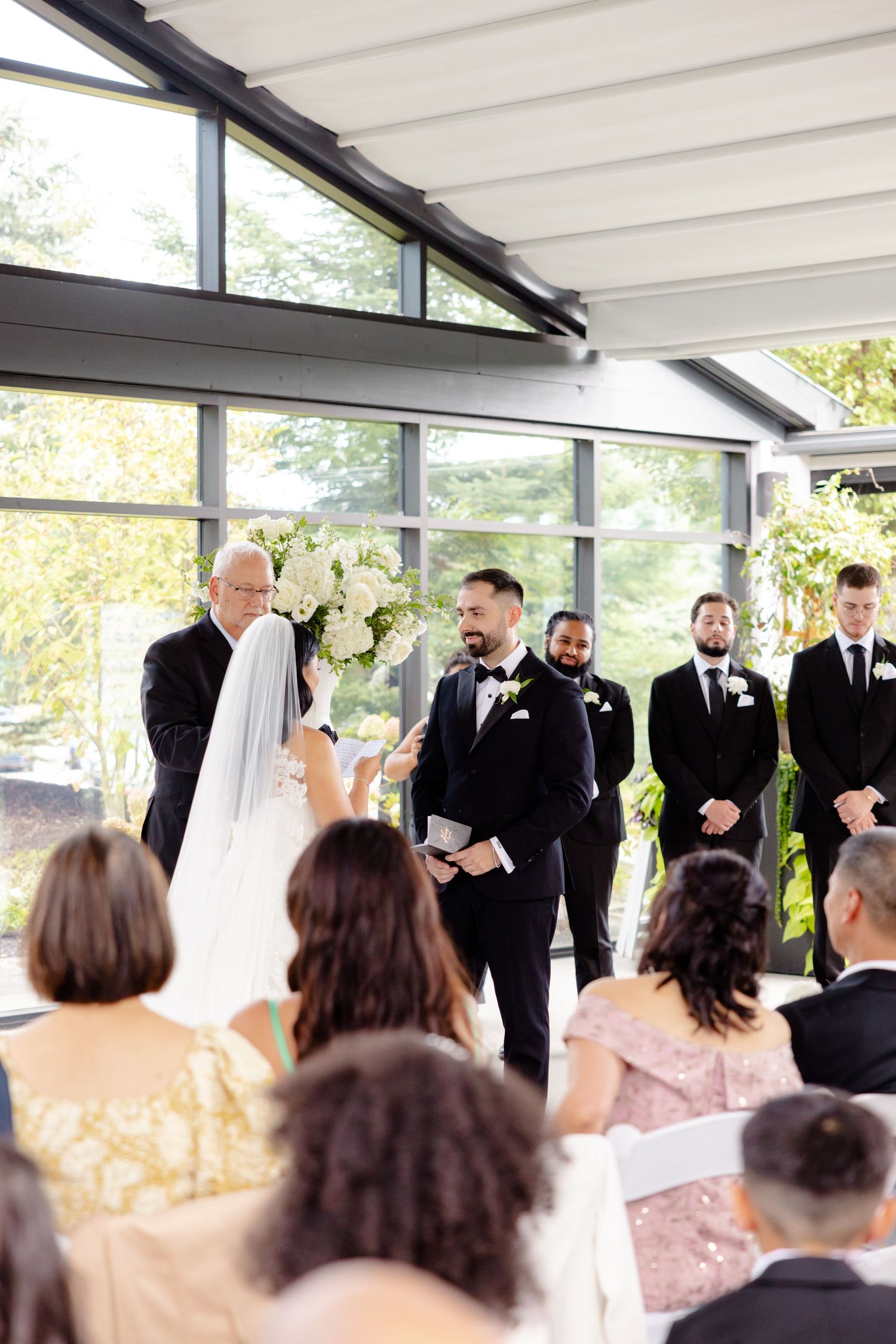 Wedding ceremony with groomsmen in black suits standing at altar.