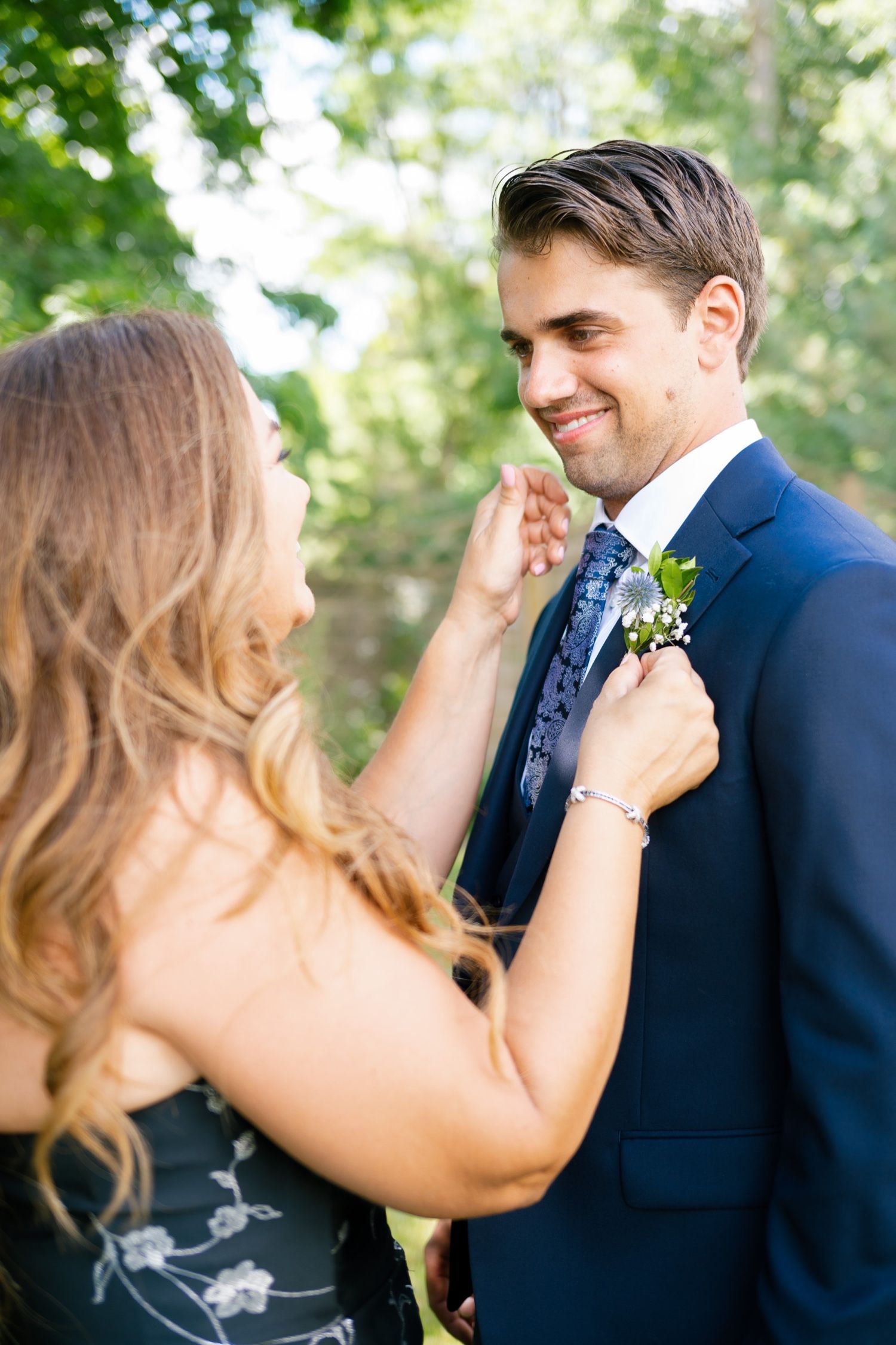 A tender moment captured outdoors with formal attire and floral boutonniere.