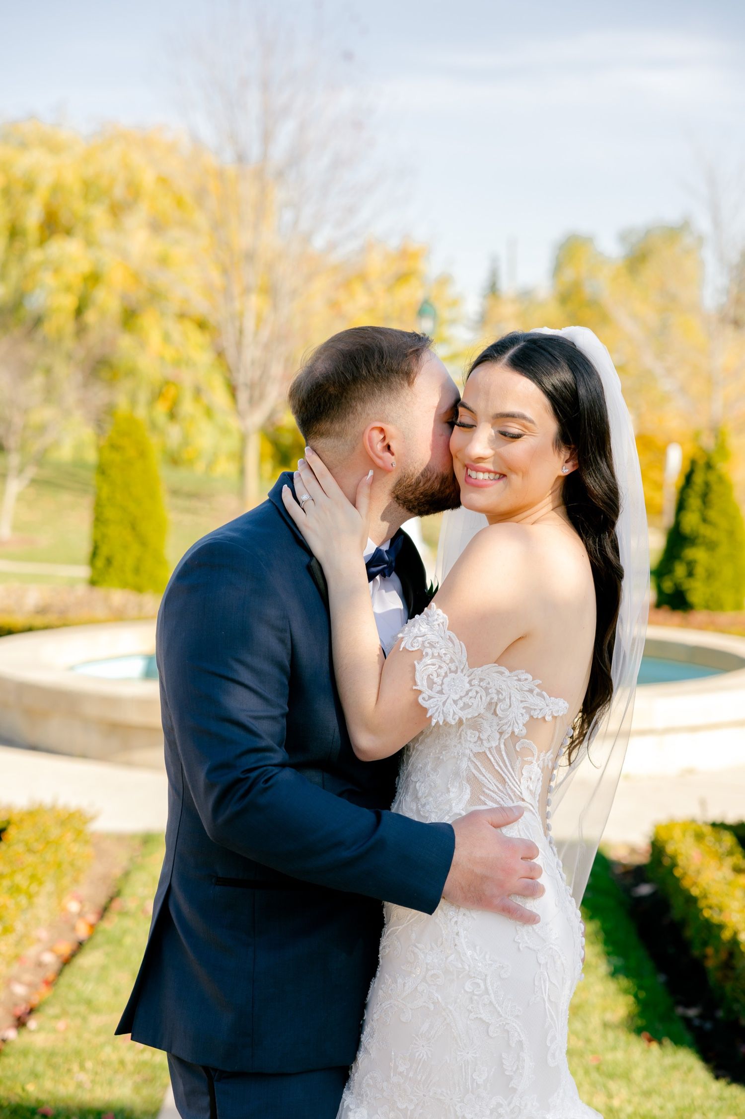 Romantic moment between newlyweds in garden with golden autumn foliage.