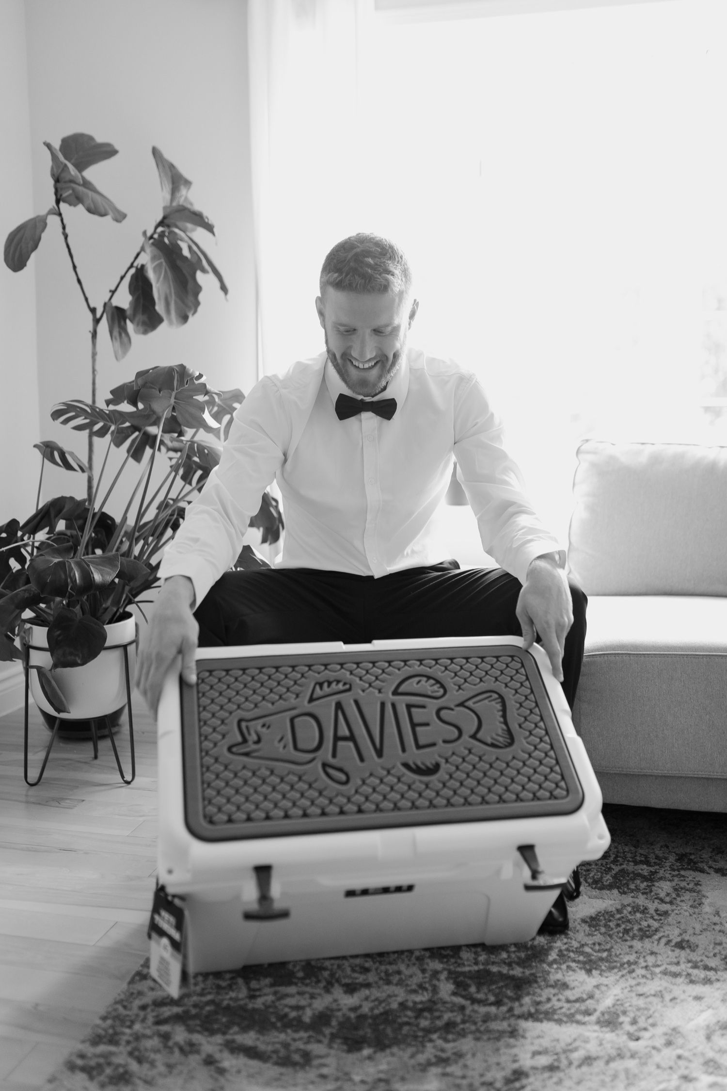 Black and white photo of person sitting with personalized box in bright living room.